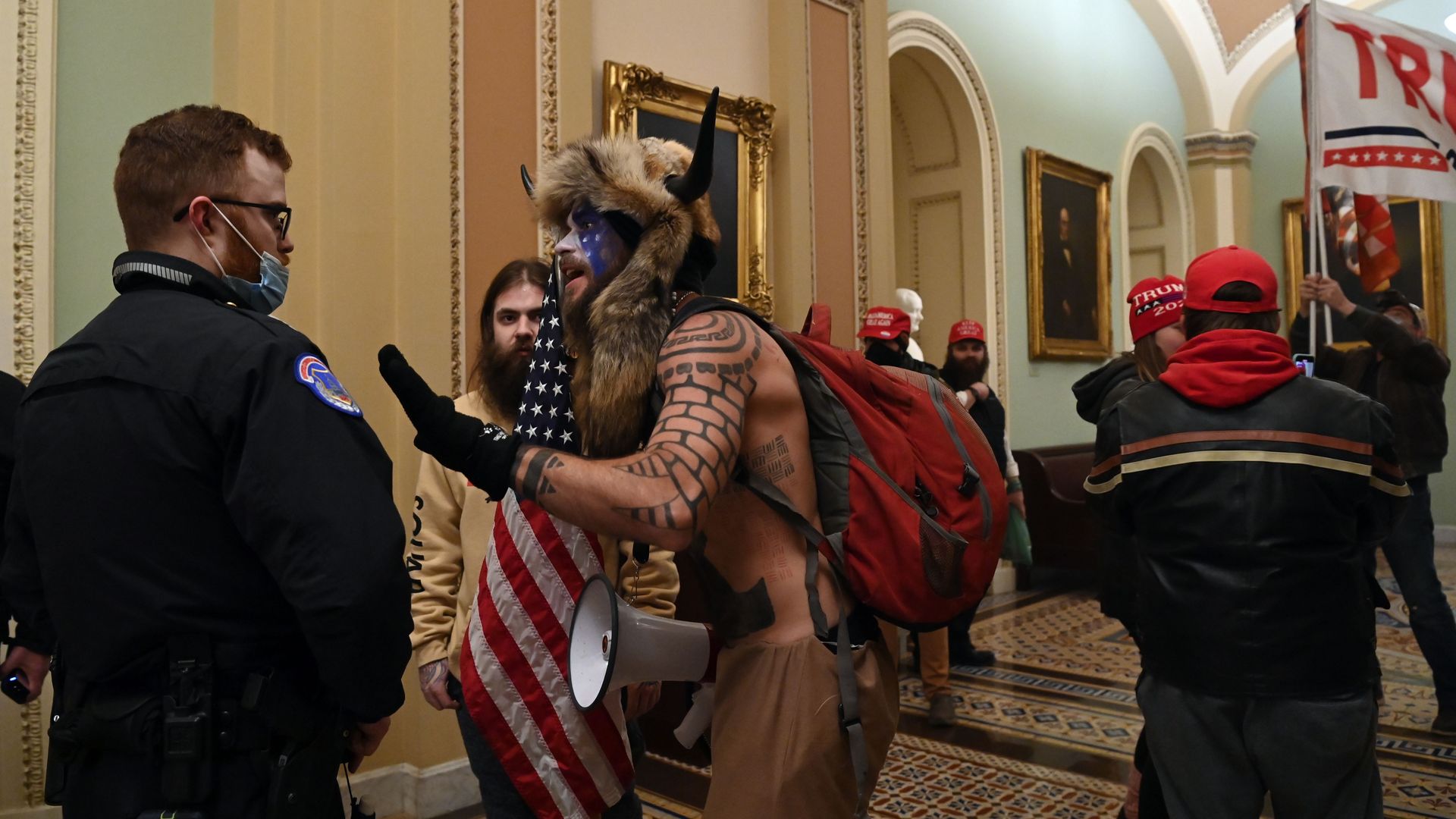 Jacob Chansley, in fur hat with horns, talks with a police officer during the Jan. 6, 2021, takeover of the Capitol by Trump supporters.