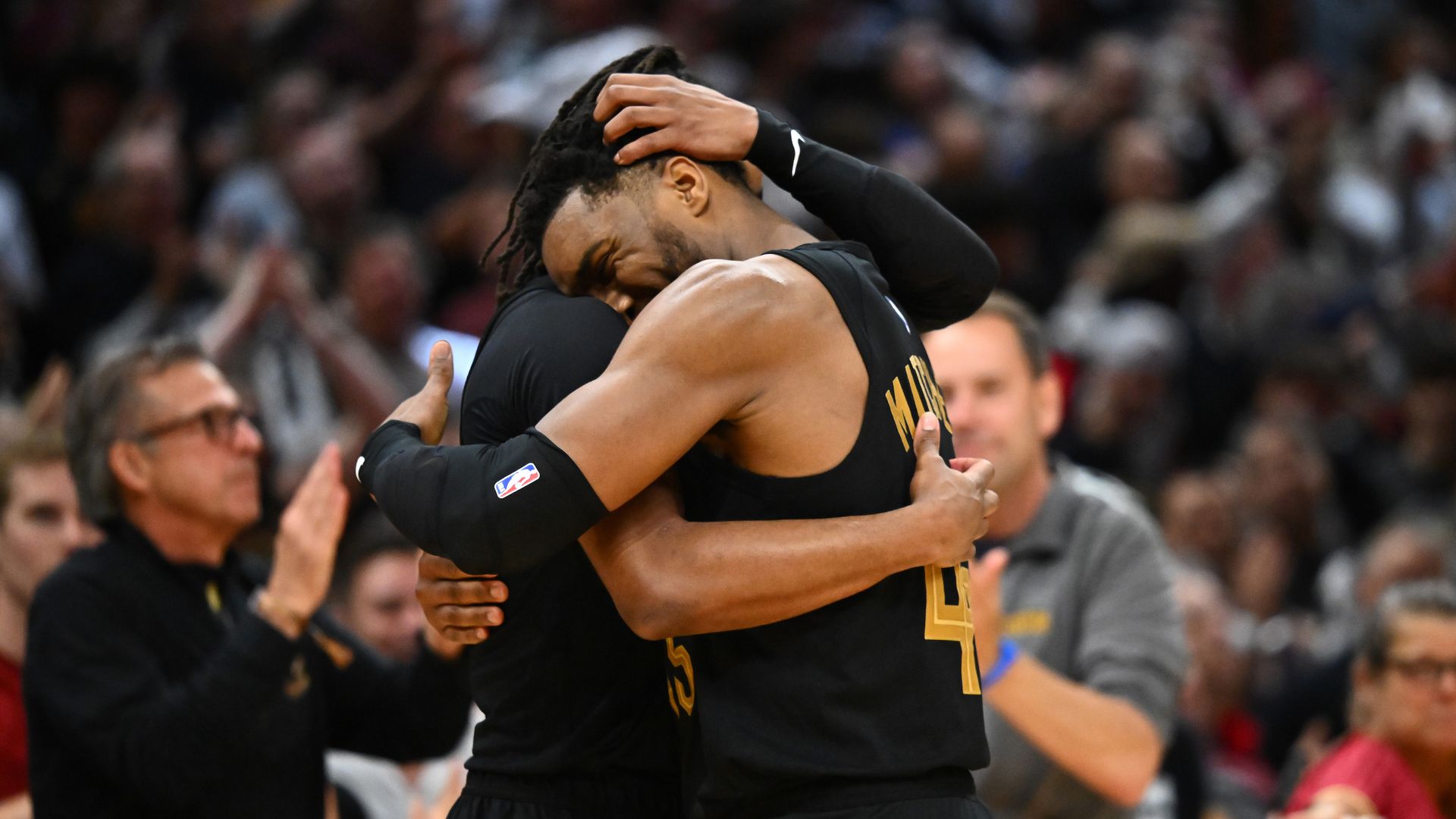 Cavs players Darius Garland and Donovan Mitchell embrace each other on the court. 
