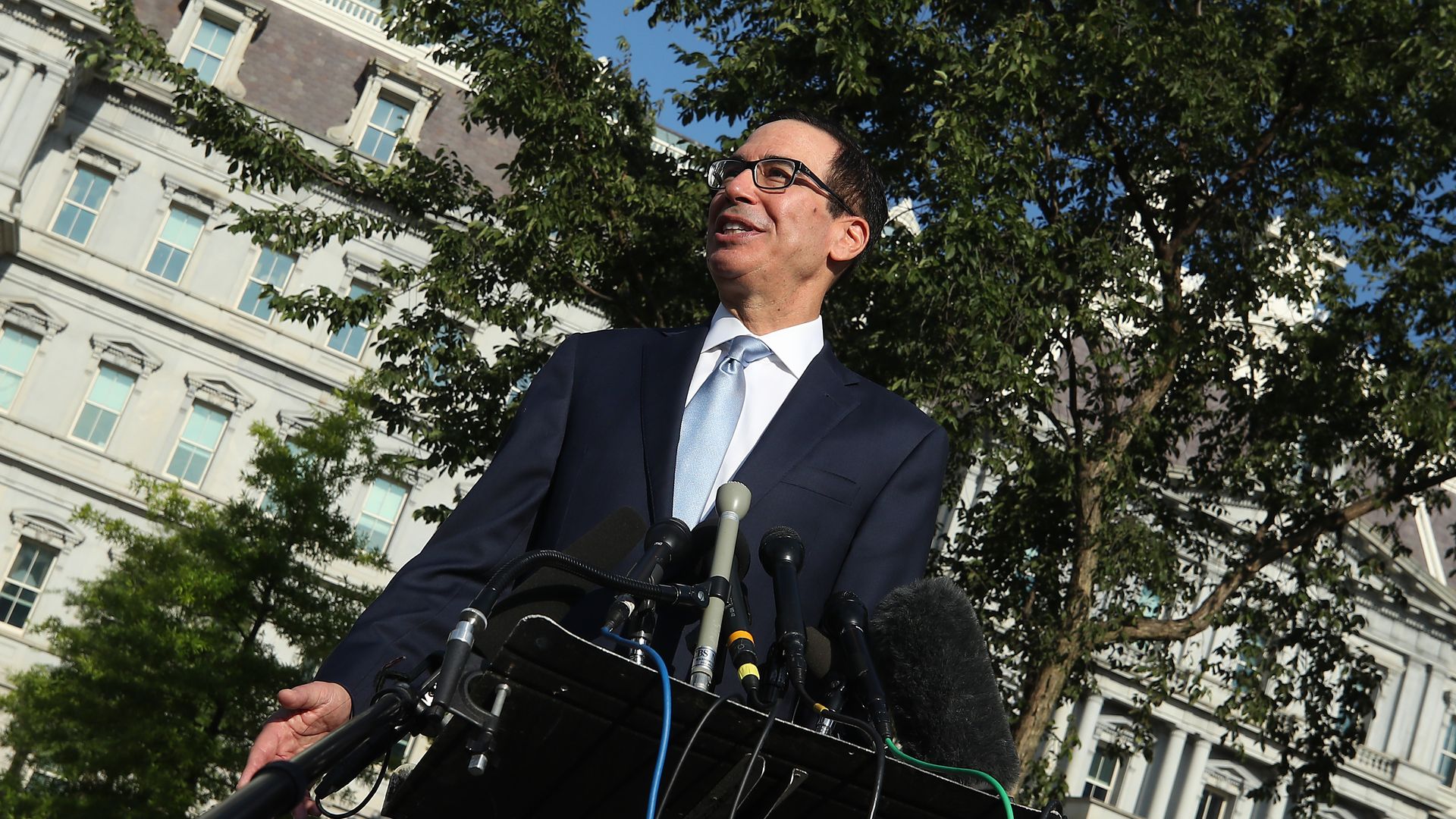 Mnuchin stands on a lawn with microphones pointed at him