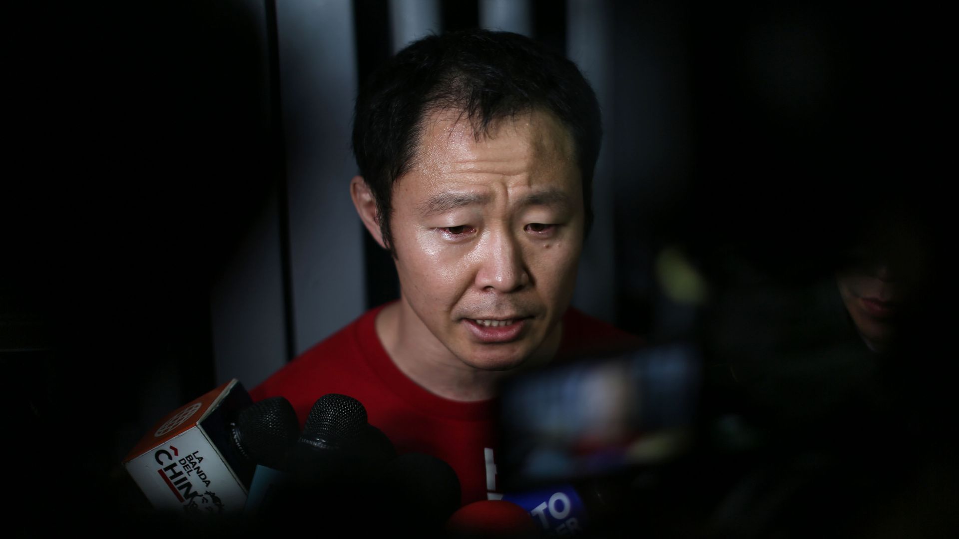 Kenji Fujimori speaks in front of a TV microphones