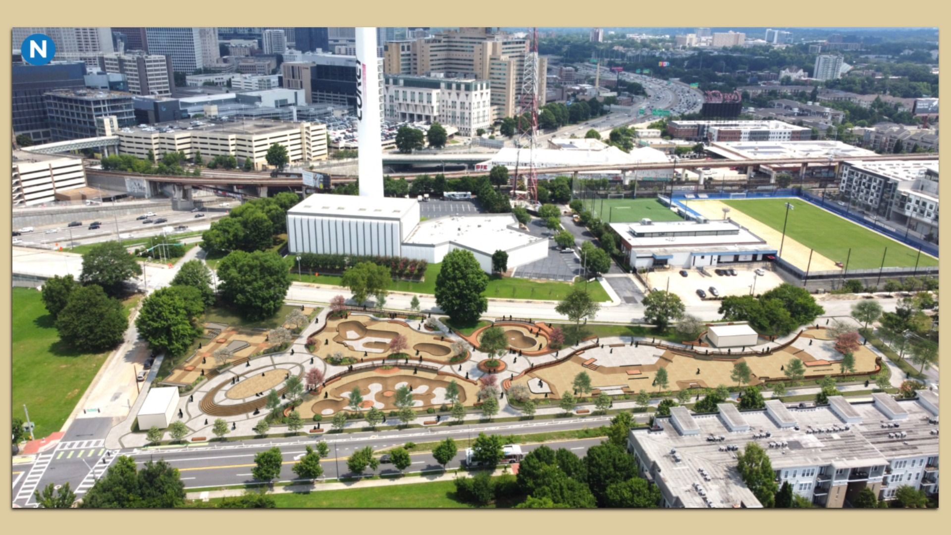 Aerial view of a city: a white modern building with a tall vertical tower, elevated rail tracks, a large sports field, and a winding ornamental park with circular patterns in the foreground.