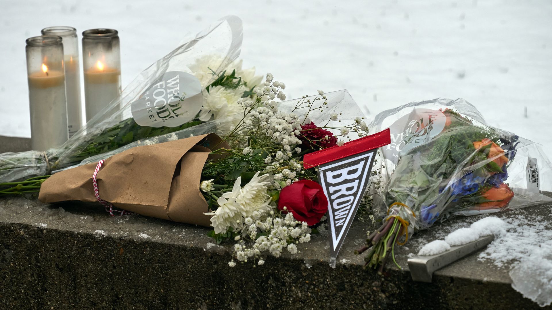 A spread of flowers and candles with a sign that says "BROWN." There's snow in the background