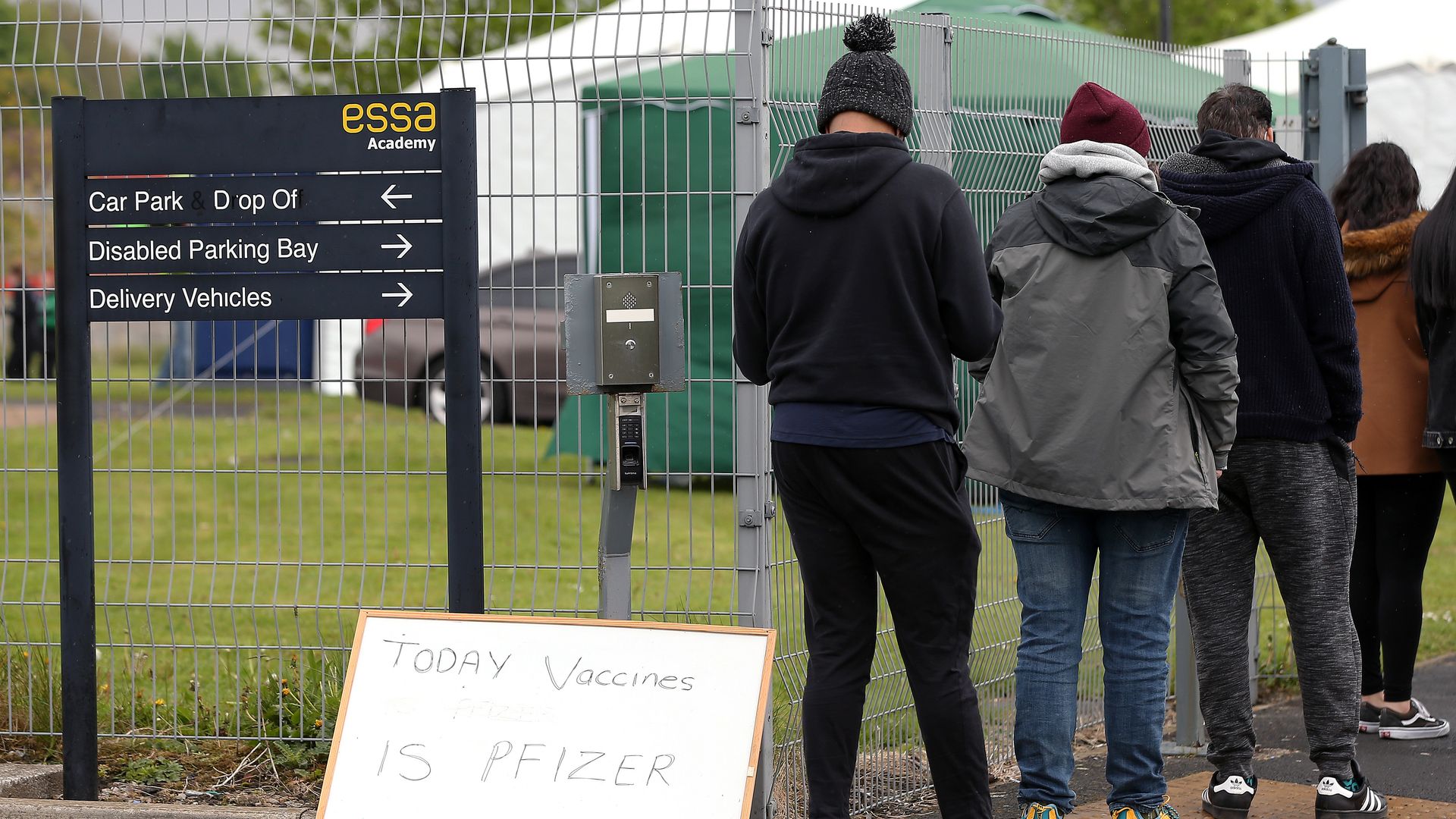 A sign reading 'Today Vaccines Is Pfizer' is seen outside Essa Academy as people queue to get vaccinated on May 15, 2021 in Bolton, England.