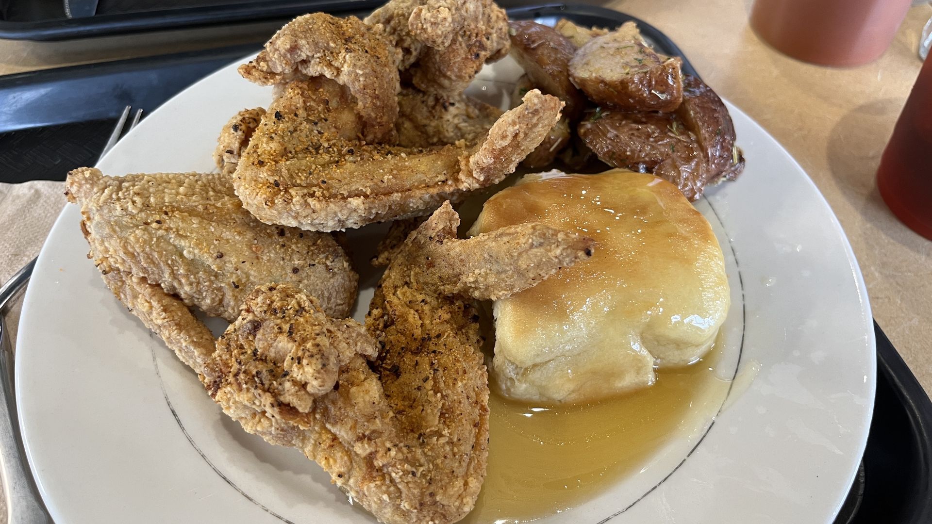 Chicken wings on a plate with a biscuit covered in honey.