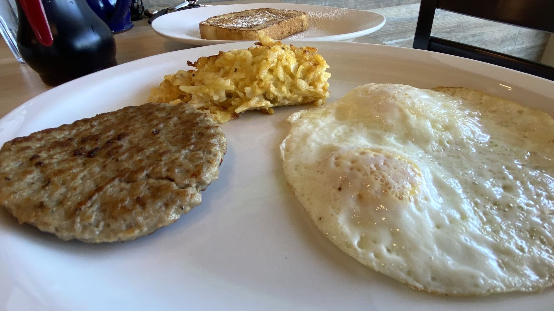 A plate of eggs, sausage patties and hash brown casserole. 