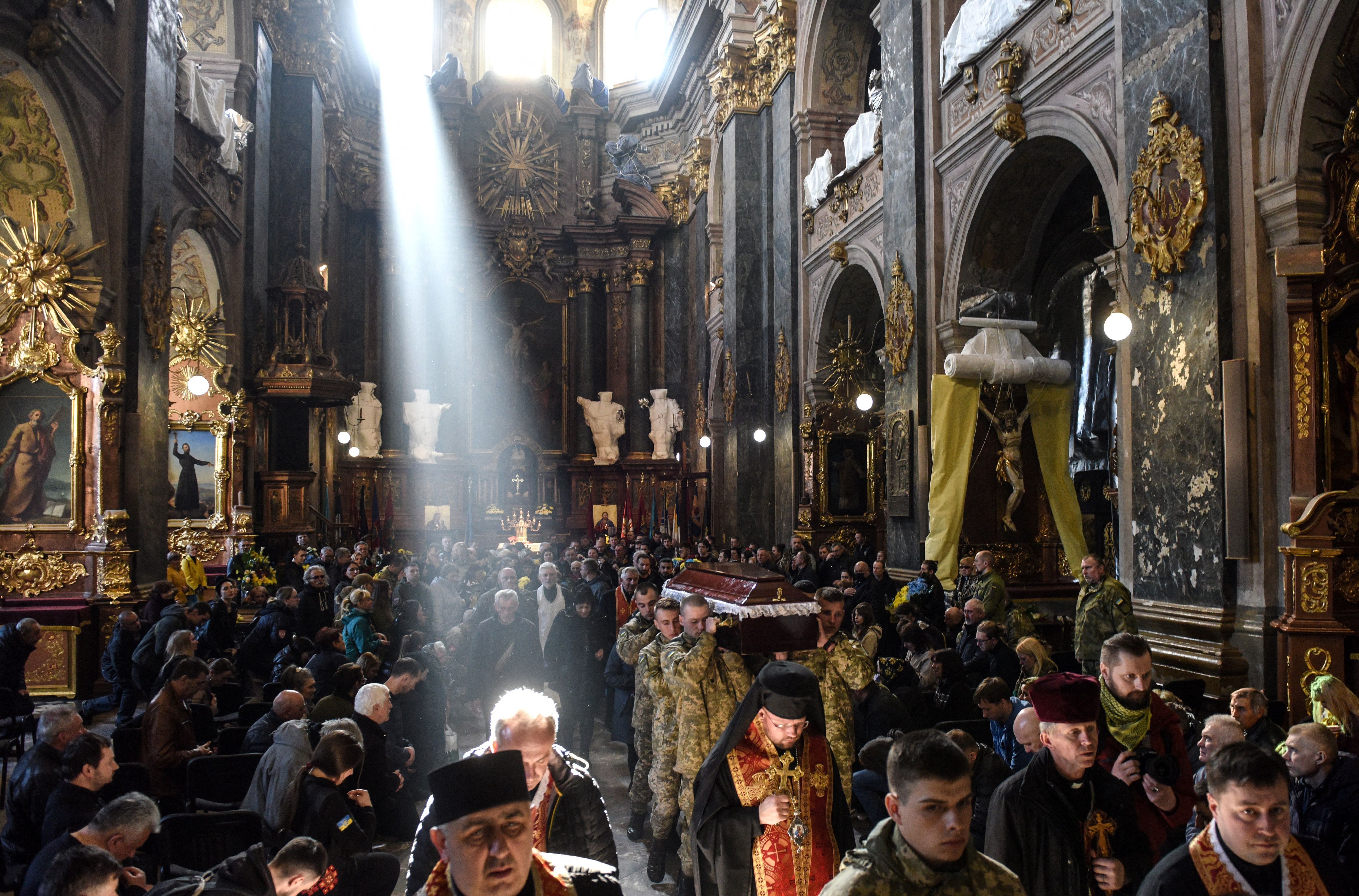 Mourners attend a memorial service for a Ukrainian services officer at the Saints Peter and Paul Garrison Church in the western Ukrainian city of Lviv on April 13.