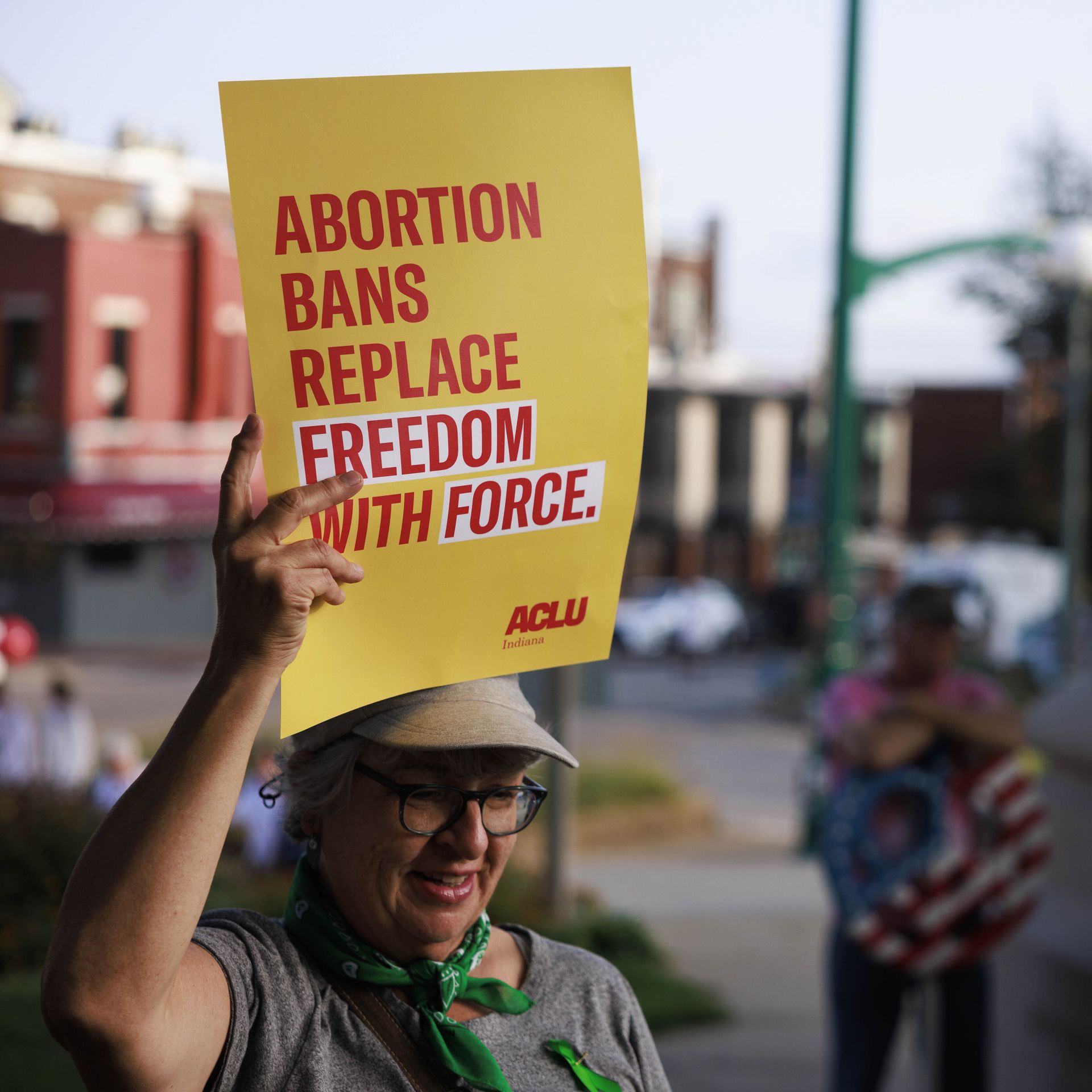 Picture of a person holding a yellow sign that says "abortion bans replace freedom with force"