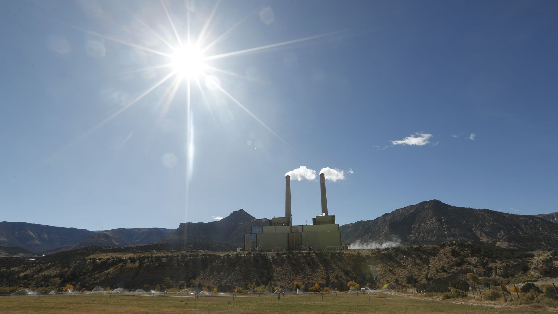 A coal power plant with the sun shining.