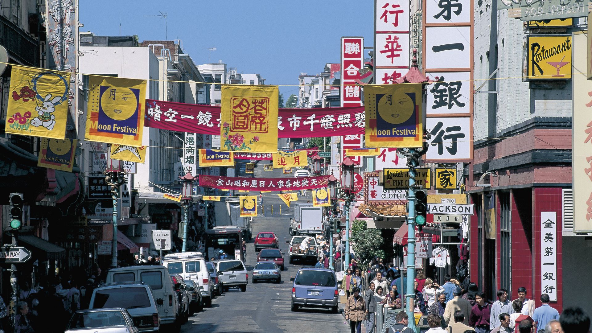 Photo of a street in Chinatown with yellow and red signs in Chinese hung across the buildings