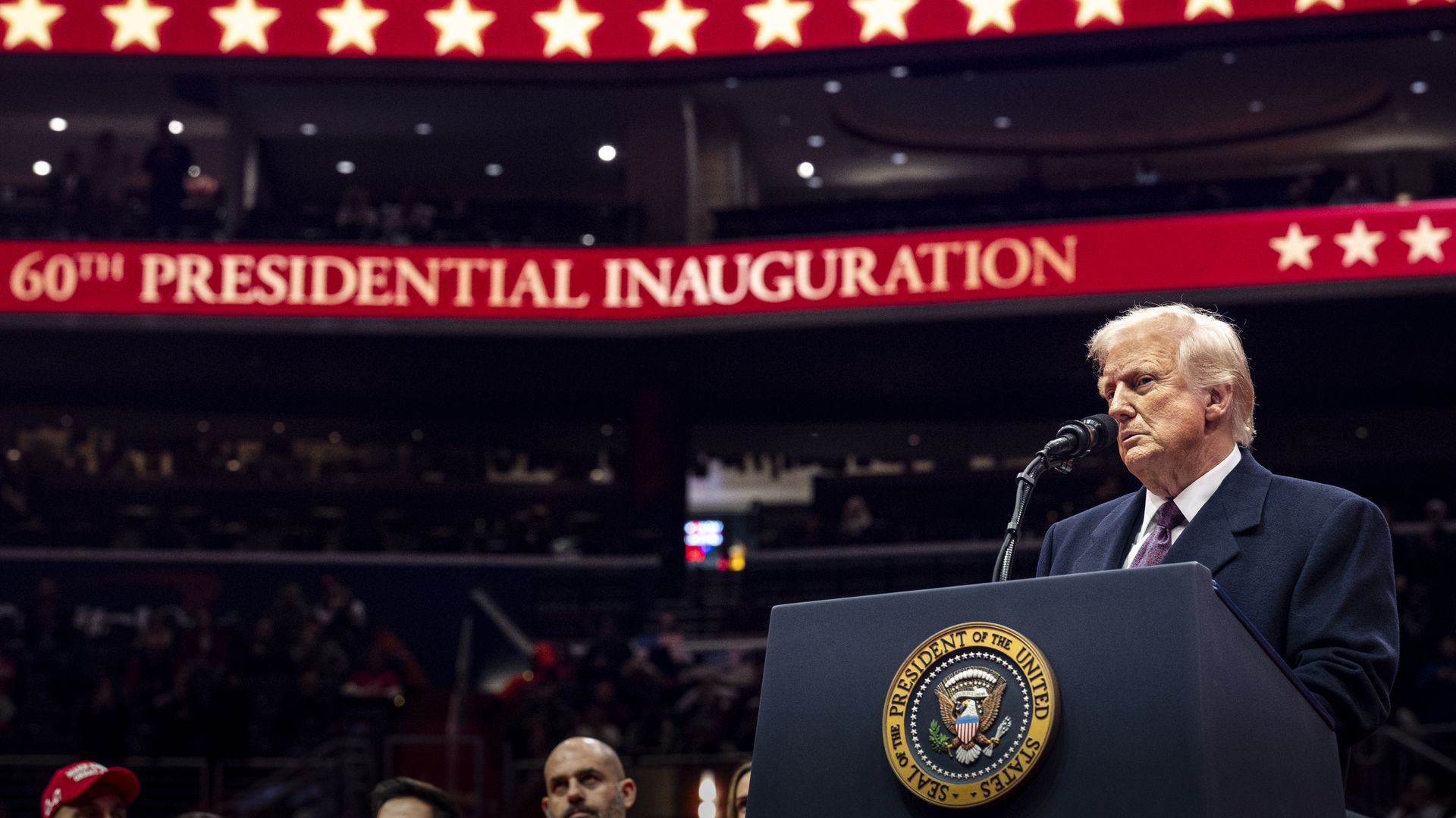 Donald Trump stands behind a podium on the right side of the photo. He is in a suit and tie. In the background, a red electronic banner proclaims: "60th presidential inauguration."