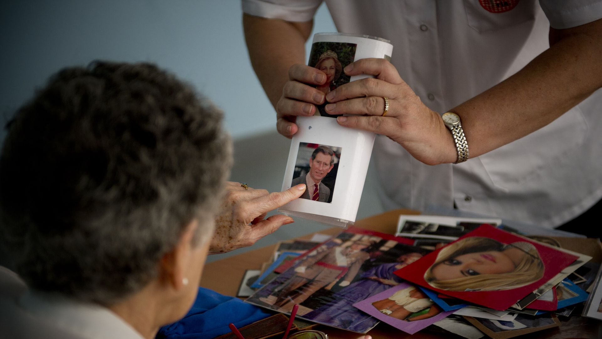 A social worker shows a portrait of Prince Charles, Prince of Wales to an elderly woman during a memory activity on August 2, 2012 in Barcelona, Spain