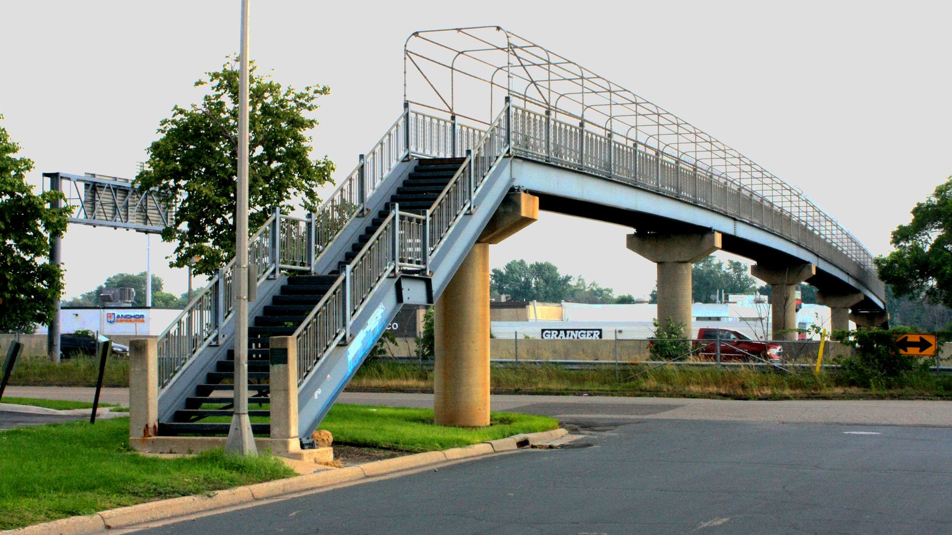 A photo of a blue bridge that goes over a highwayl.