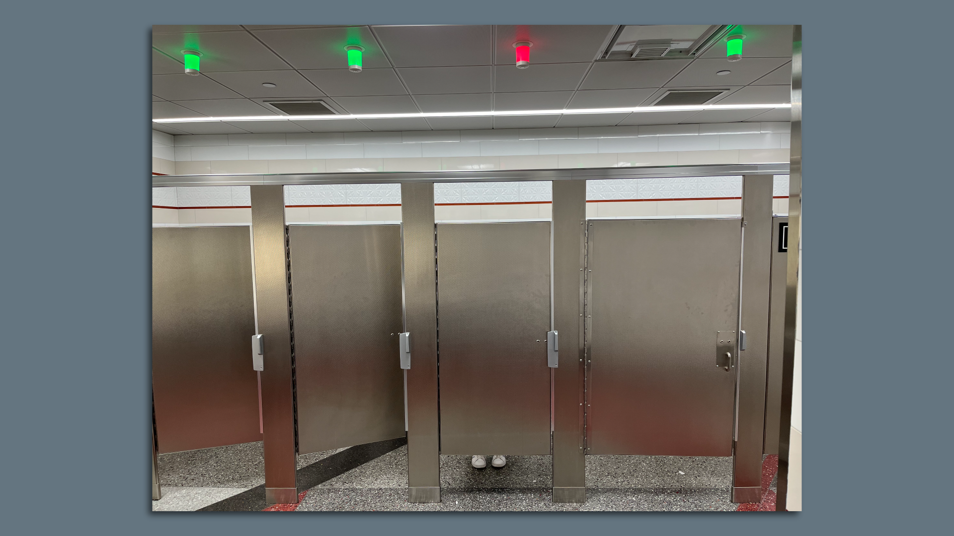 A restroom with lights overhead indicating which stalls are filled.