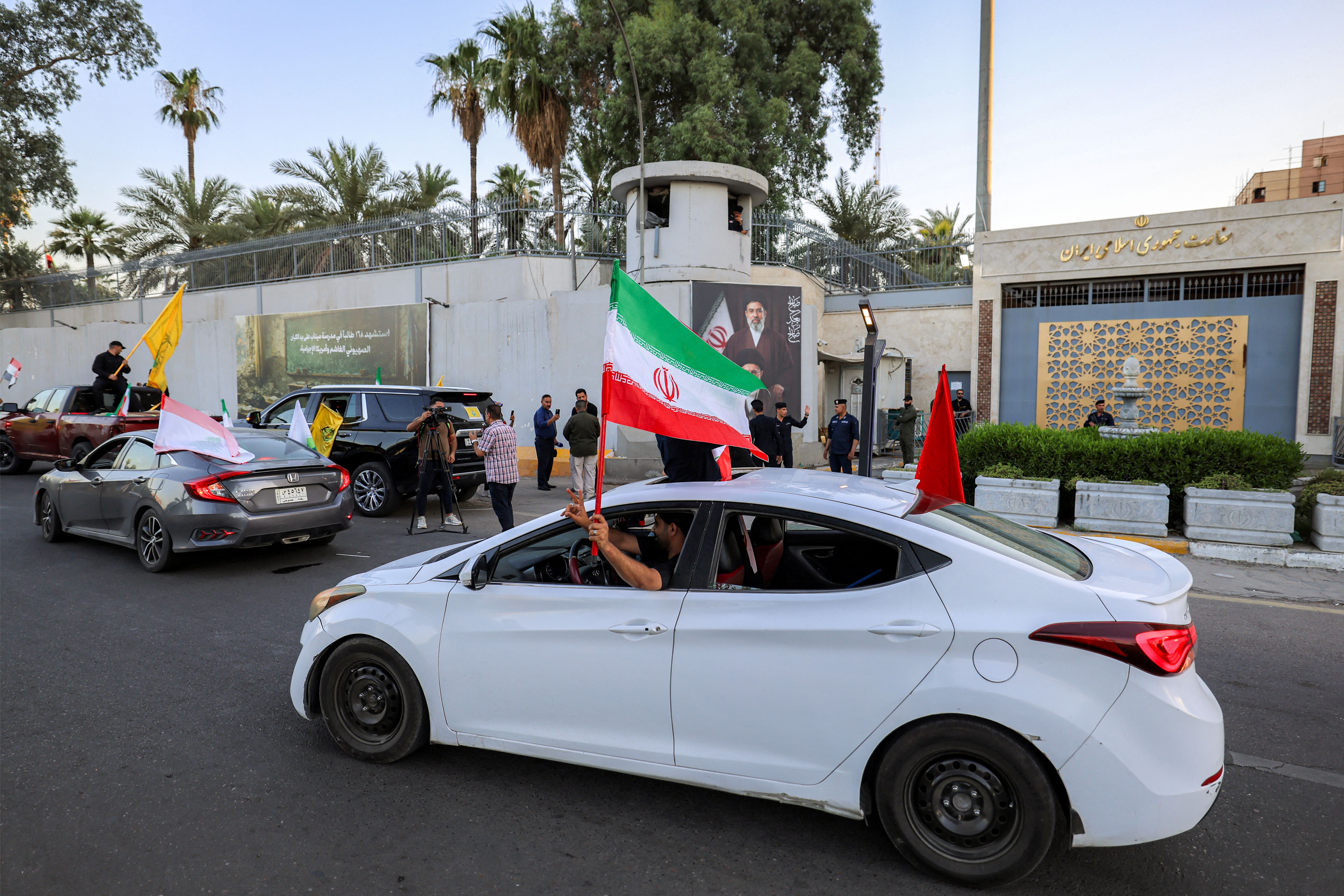 People wave the Iranian flag outside the Iranian embassy in Baghdad today. Photo: Ahmad Al-Rubaye/AFP via Getty Images