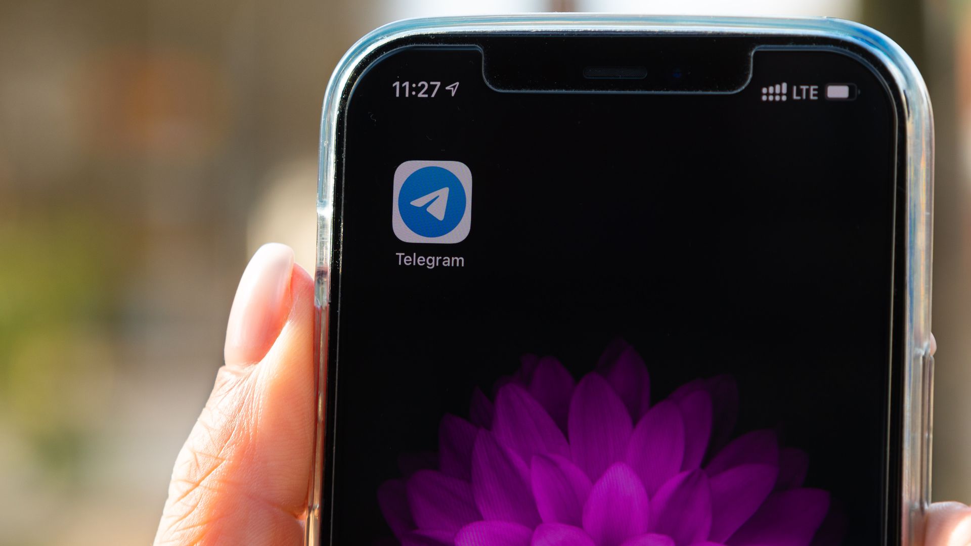 An image of a hand holding a mobile device showing only one app on its home screen, that of the Telegram messaging app.