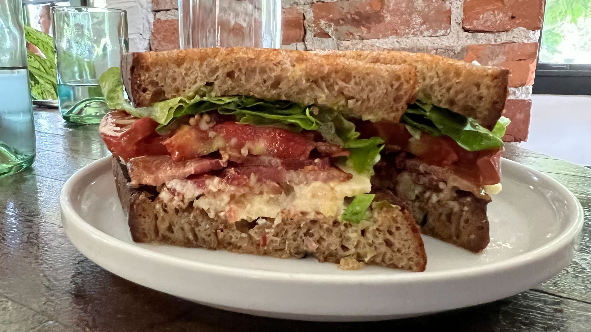 A BLT sandwich sliced in half on a plate.