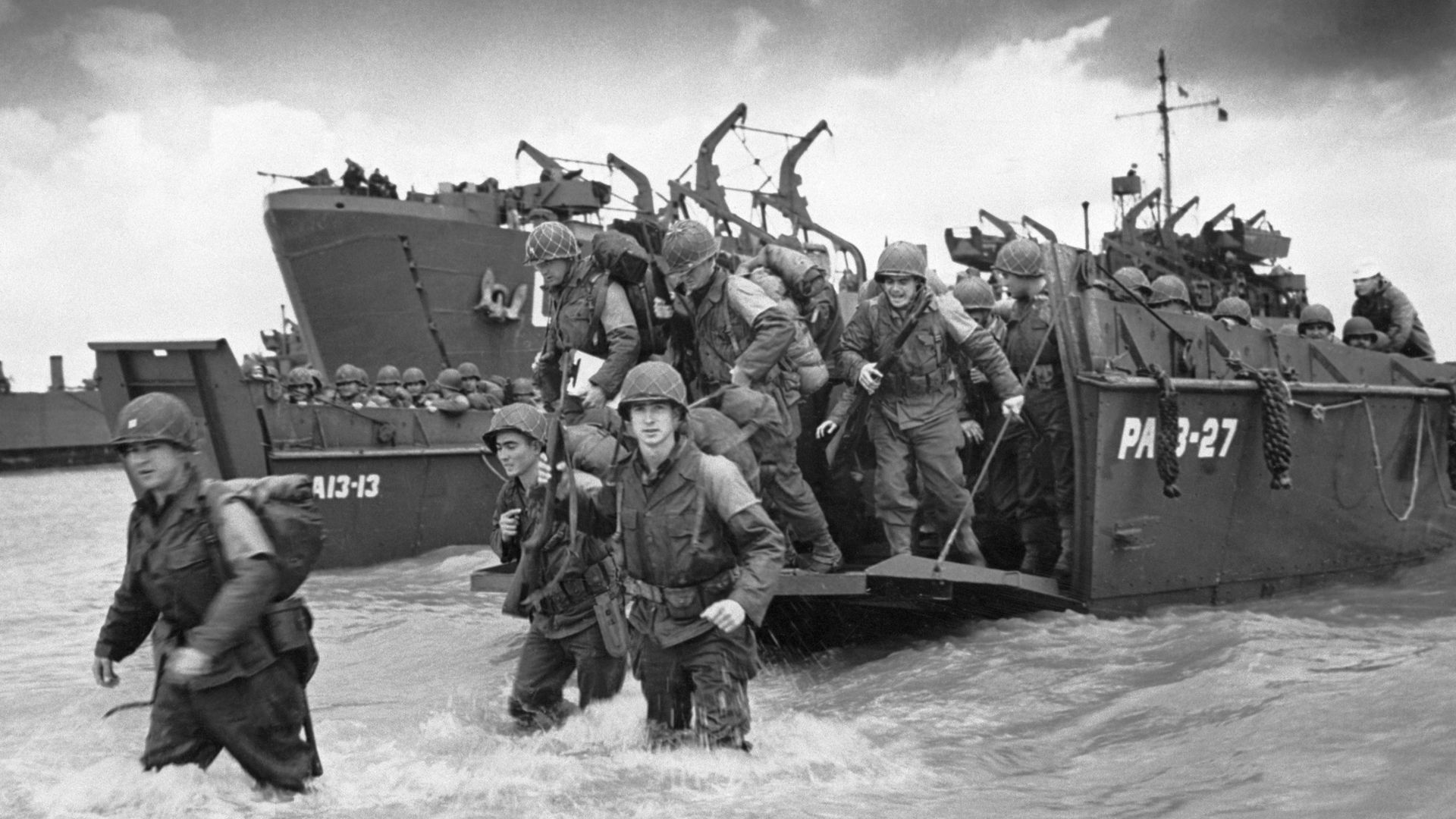 Image shows soldiers getting off a Higgins boat in Normandy.