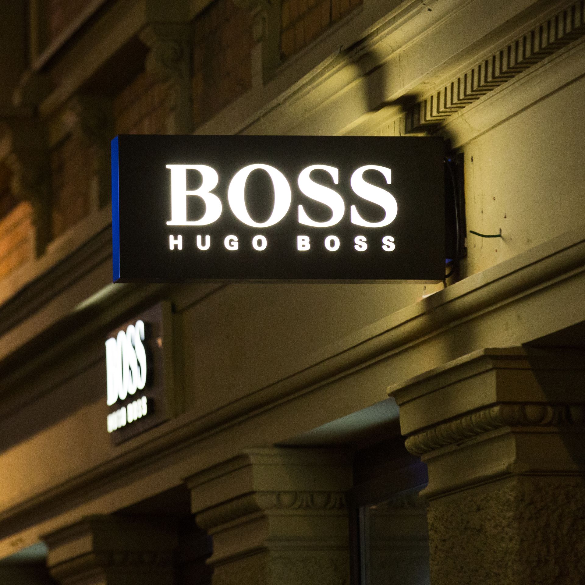 A lighted Hugo Boss sign hangs above a storefront.