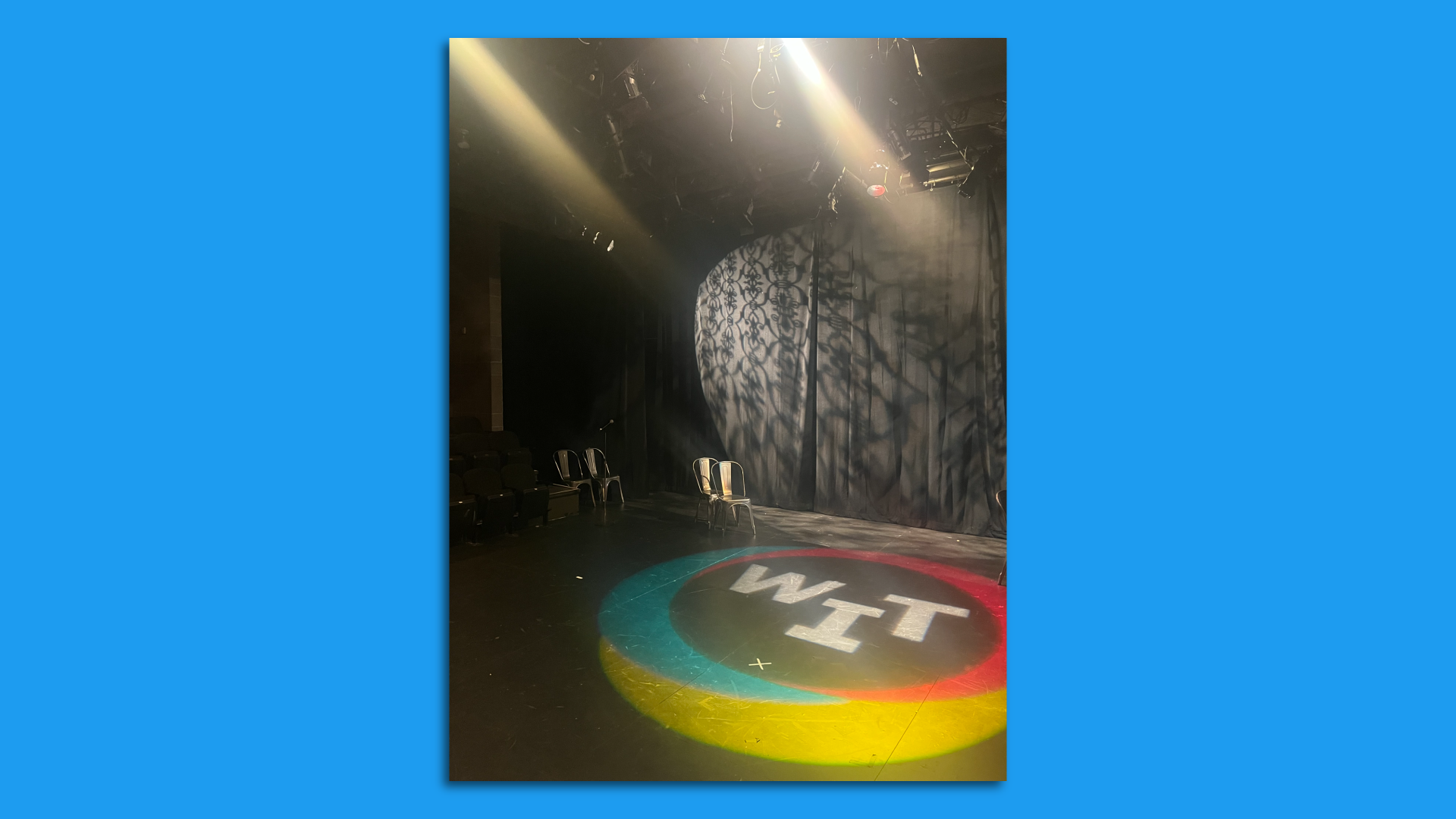 A photo showing an empty stage with the letters "WIT" projected onto it.