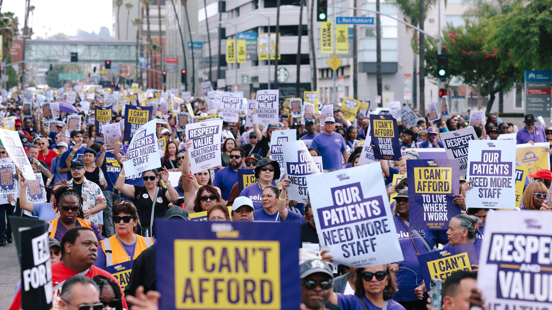 A group of people walking down the street all holding protest signs.