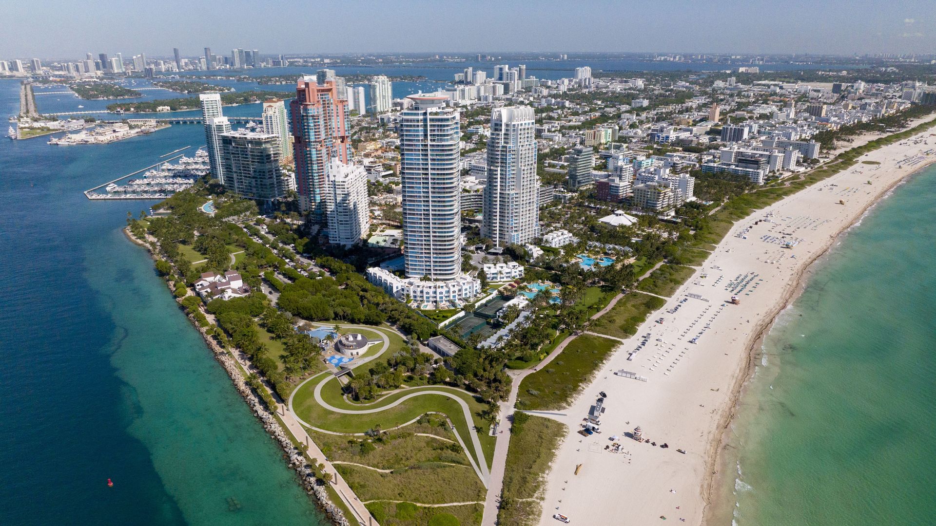 An aerial view of condominiums towering over a beachfront park