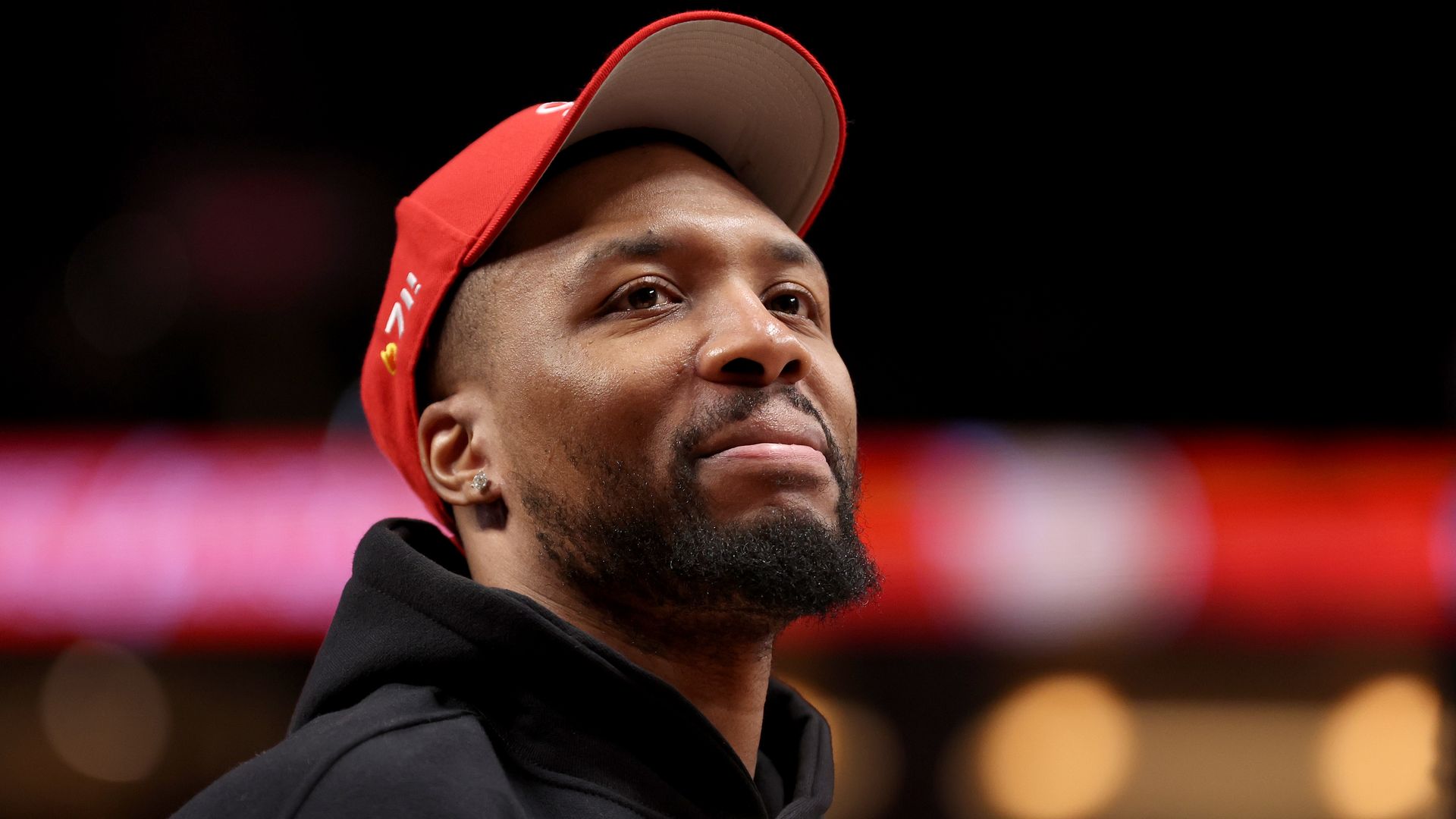 A basketball player in a red baseball cap looks into the distance.