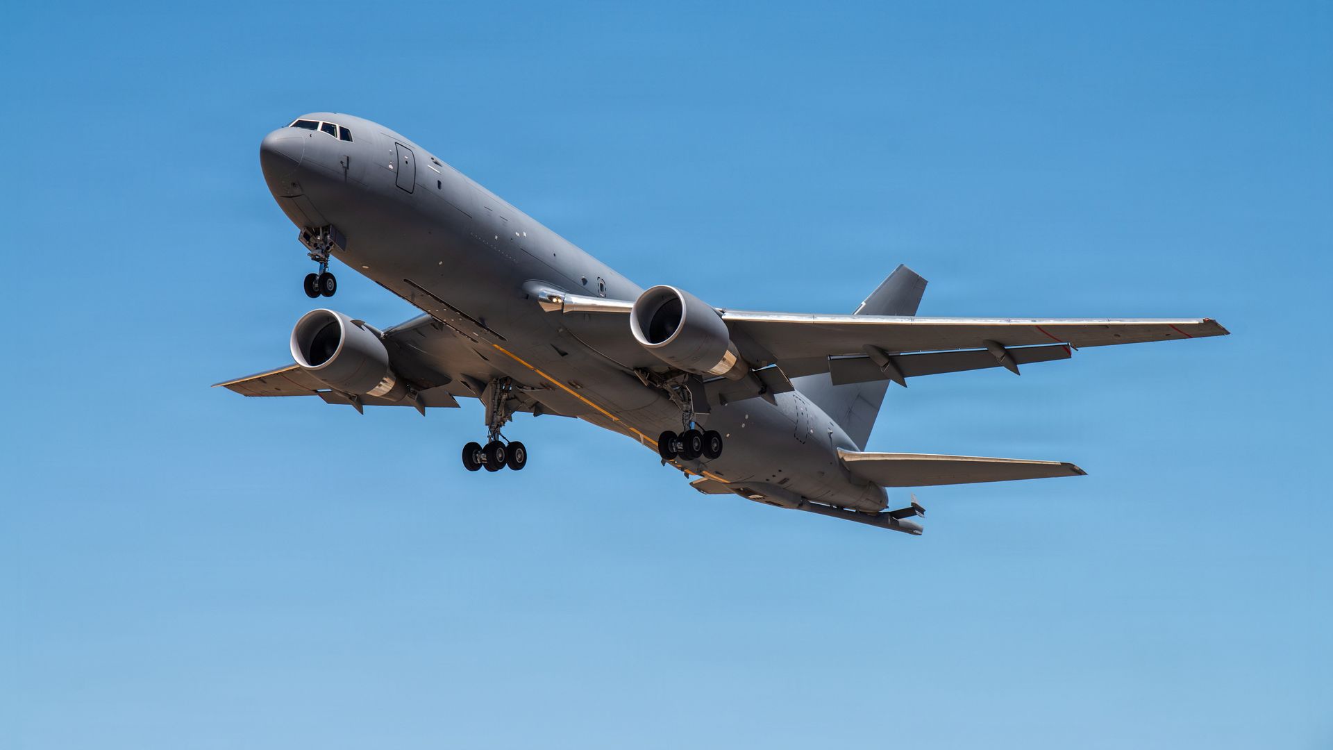 A large grey-in-color tanker aircraft pictured against a clear blue sky.