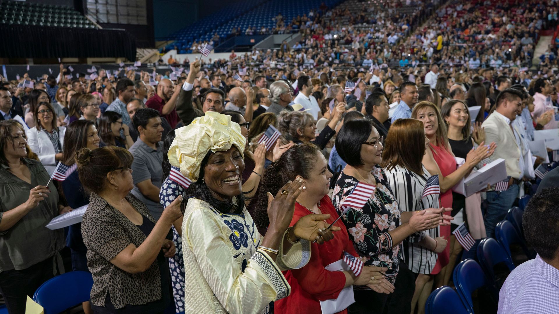 A diverse crowd of new Americans at a naturalization ceremony.