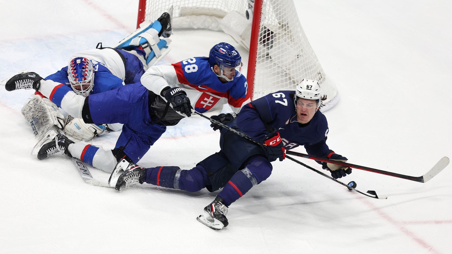 Matt Knies #67 of Team USA and Martin Gernat #28 of Slovakia fall pursuing the puck in overtime during the Men’s Ice Hockey Quarterfinal match at the Beijing Olympics Feb. 16.