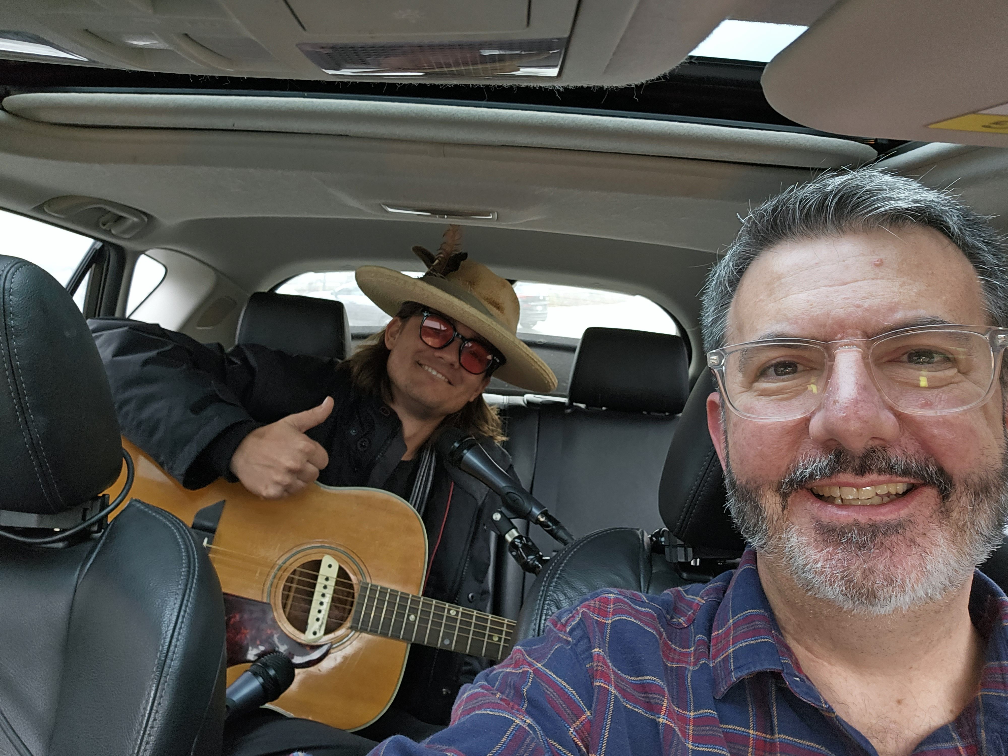 Photo of a man in a car playing guitar 