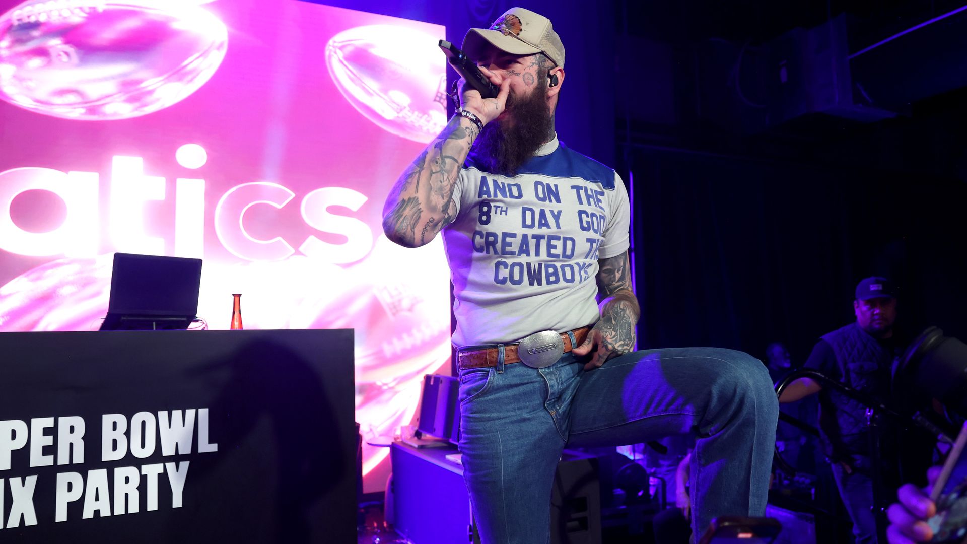 Post Malone performing while wearing a shirt that reads, "And on the 8th day god created the Cowboys."