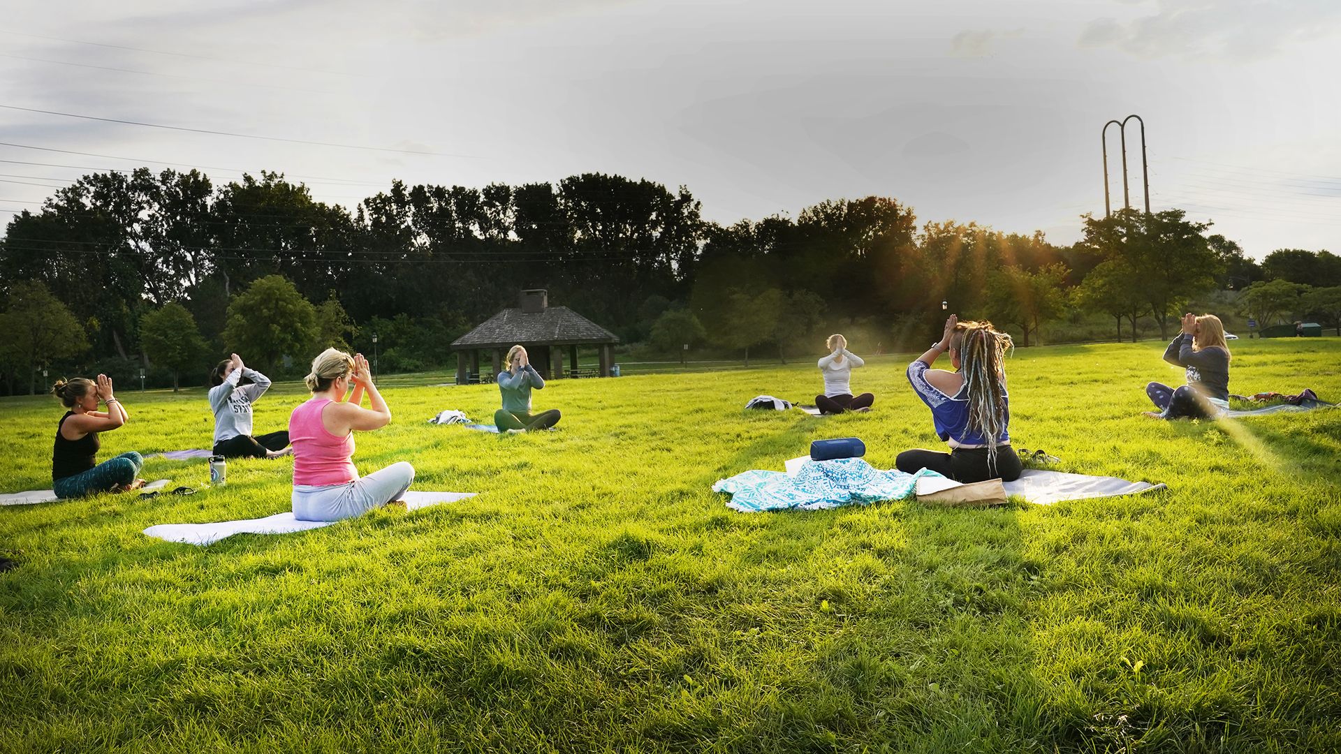 people sit in a circle doing yoga in a park on grass
