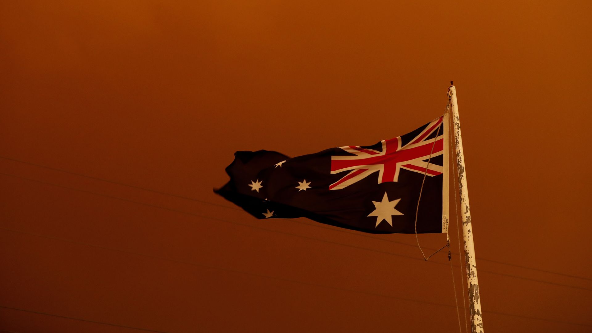 In this image, the Australian flag is seen behind a red sky.