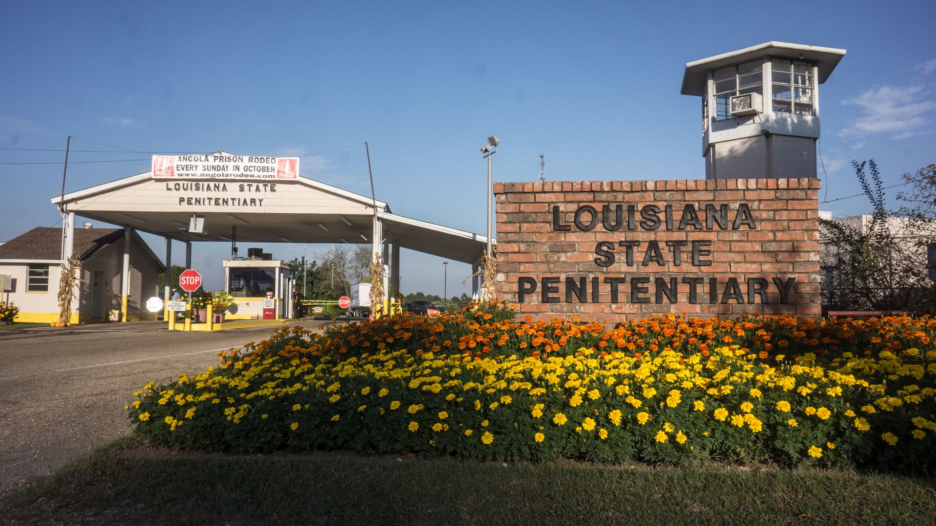 Photo of the entrance to the Louisiana State Penitentiary, which has a brick sign and flowers