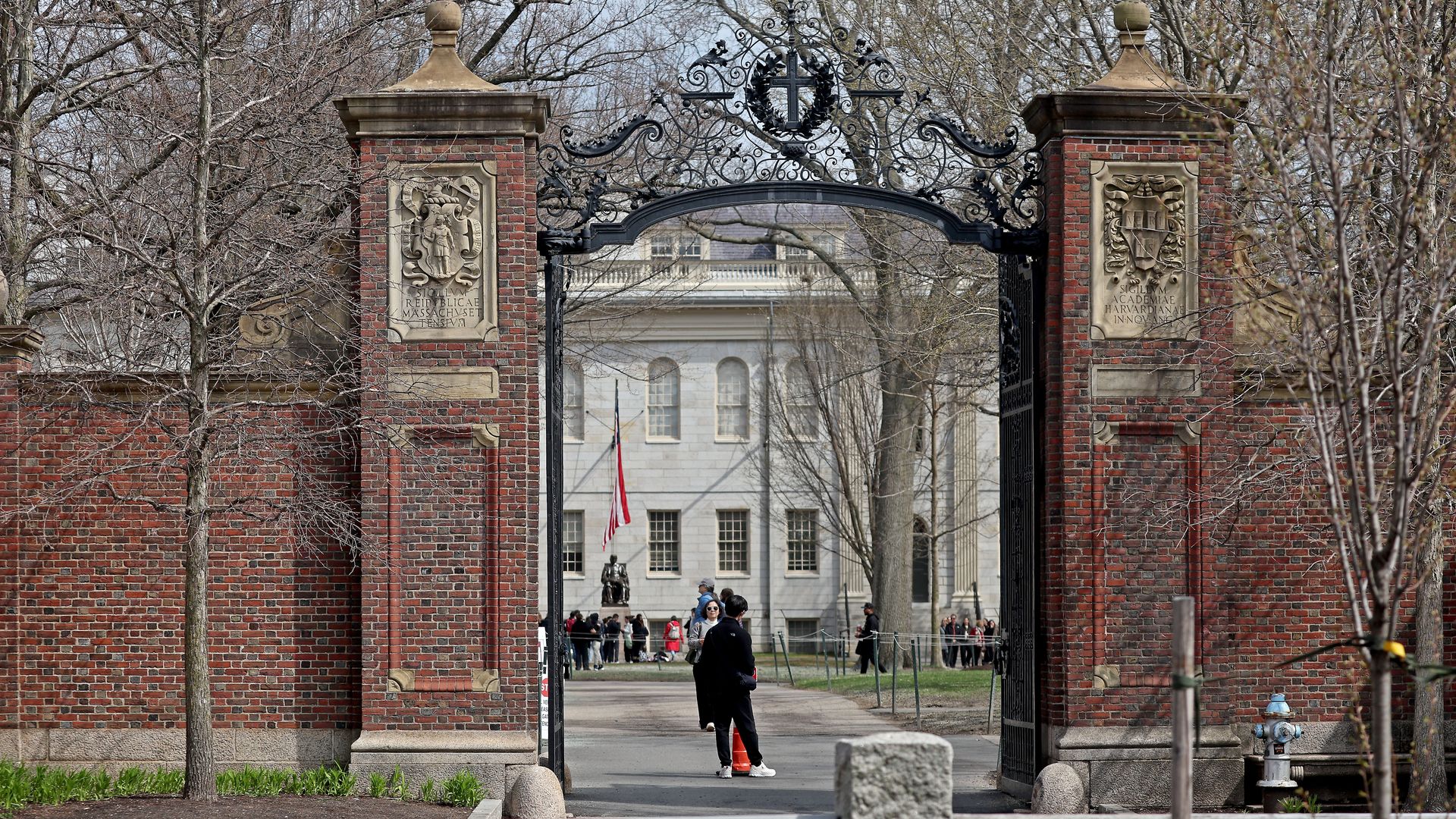 A person is seen in the distance walking through the open entrance to Harvard Yard in Cambridge, Massachusetts. 