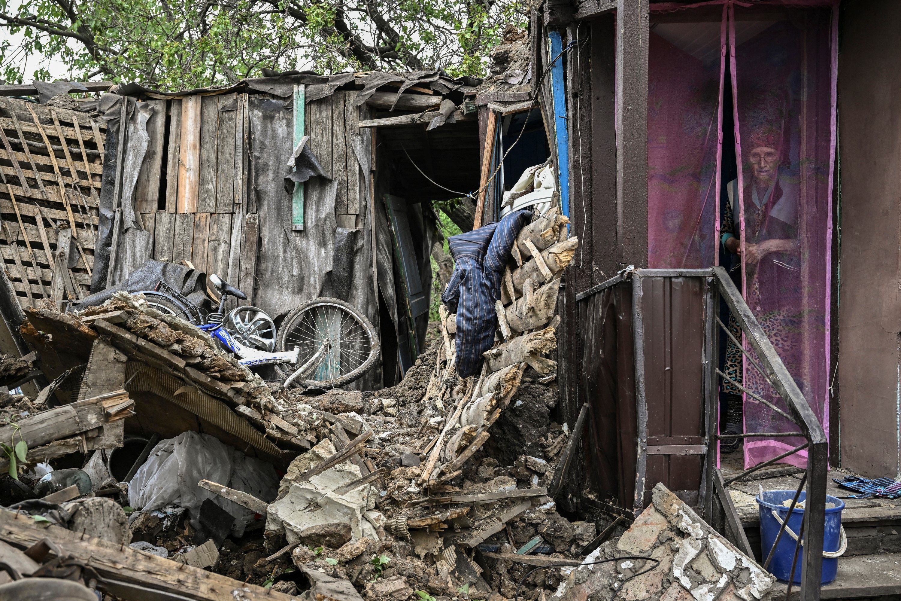 An eldery woman stands inside her heavily damaged house after it was hit by a missile in the city of Bakhmut at the eastern Ukranian region of Donbas on May 22
