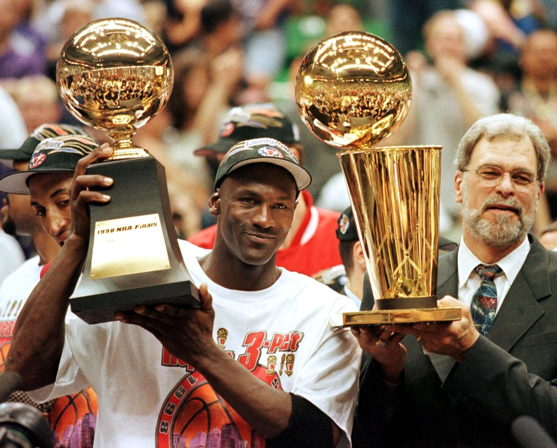 Photo of two men holding up trophies. 
