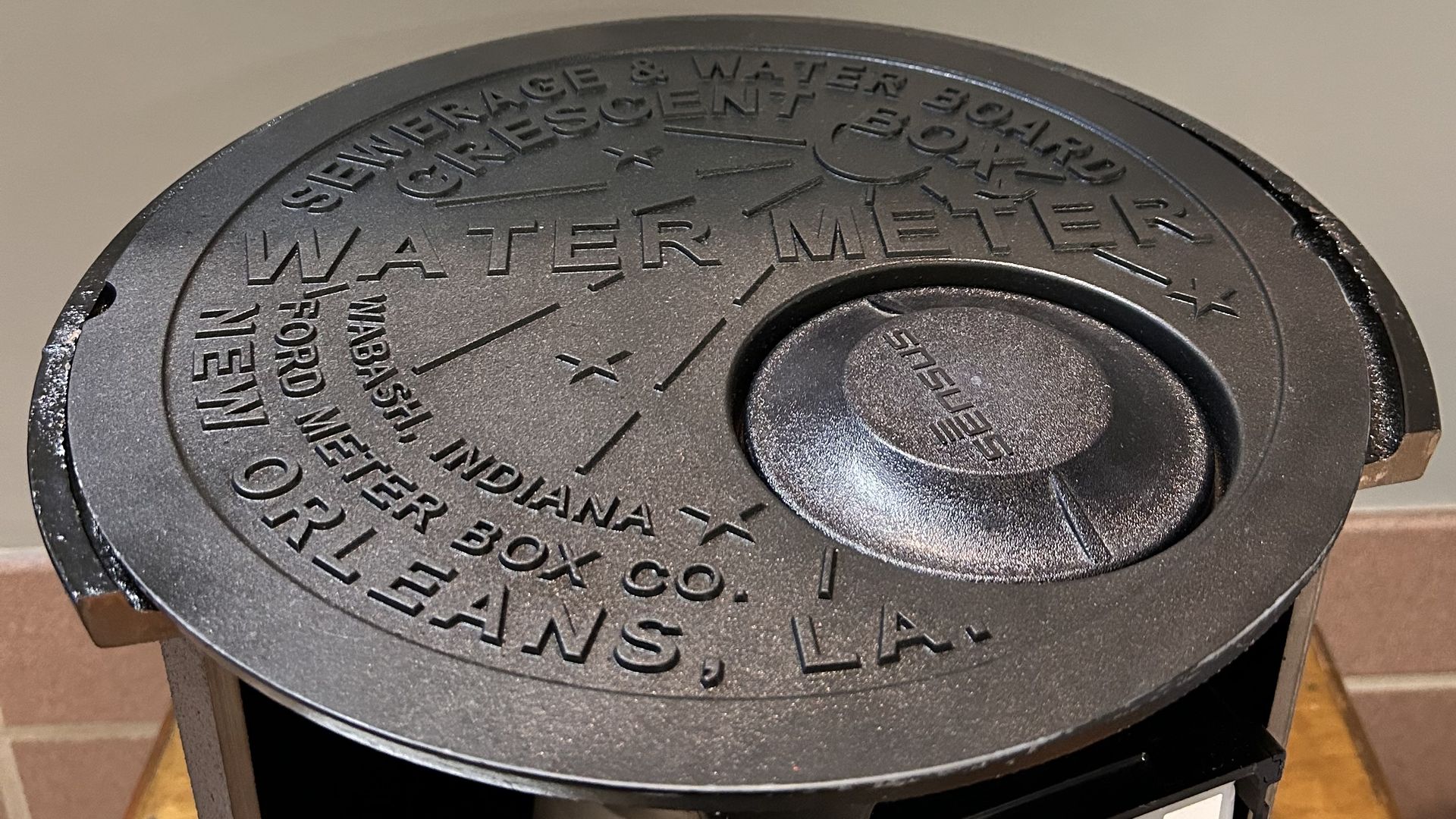 The top of a new water meter cover design for New Orleans shows clear inspiration from the 100-year-old stars and crescent moon design, but with a small circle cutout on one side with a plastic insert.