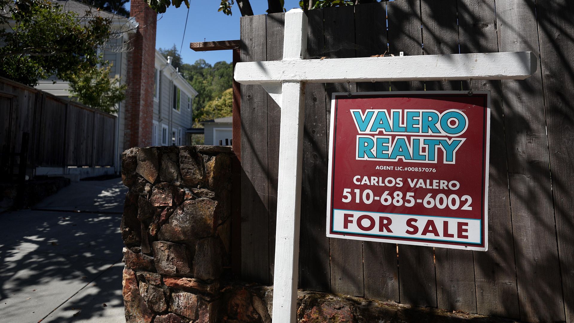 A for-sale sign is visible in front of a fenced-in residential property.