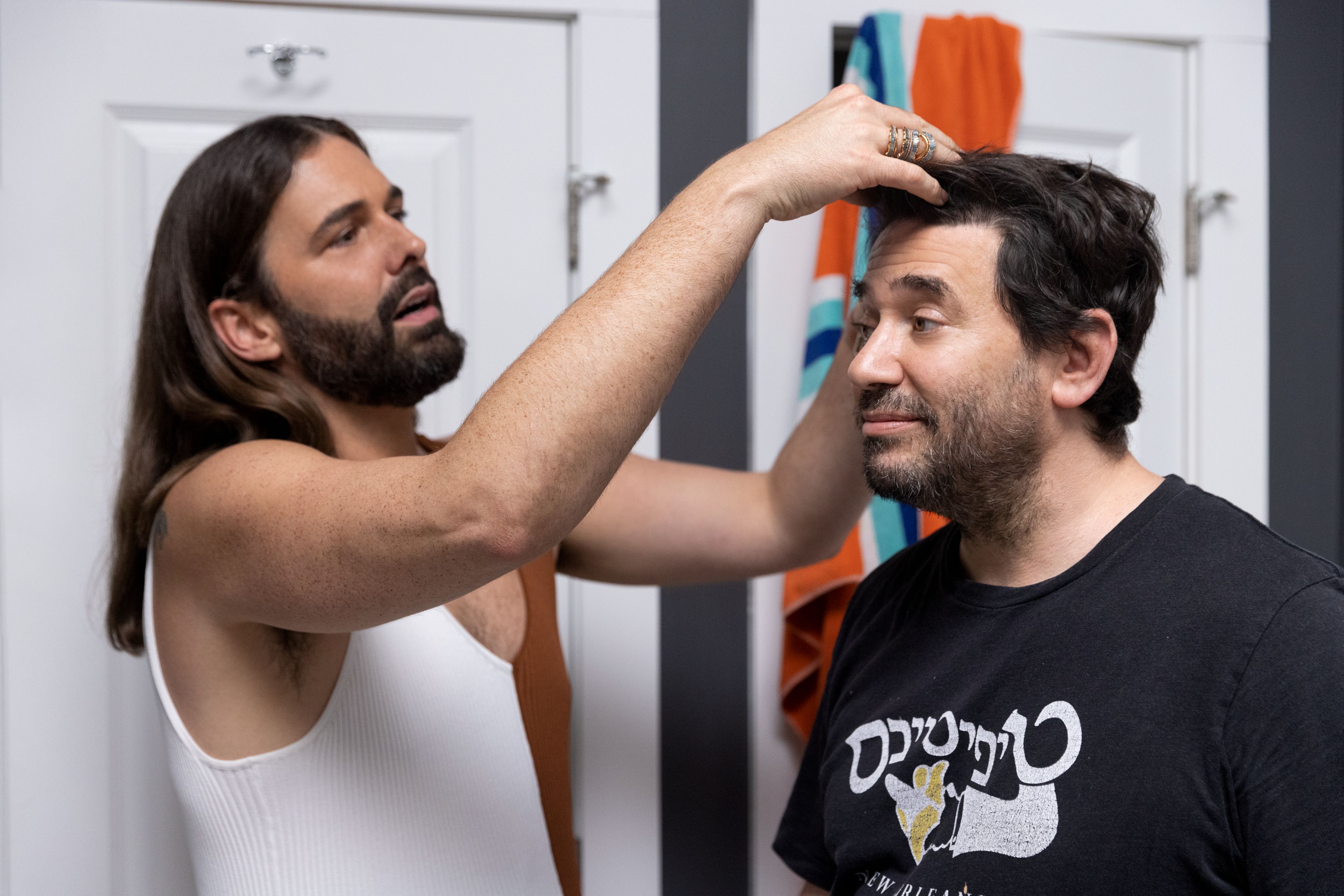 Jonathan Van Ness sinks their hands into Dan Stein's hair, who looks on apprehensively. 