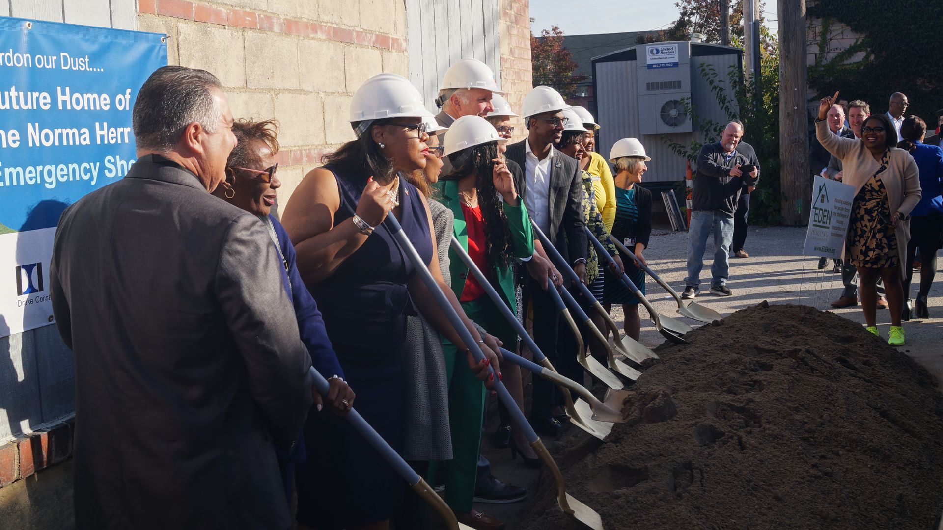 Photo of leaders in white hard harts holding shovels, ceremonially breaking ground 