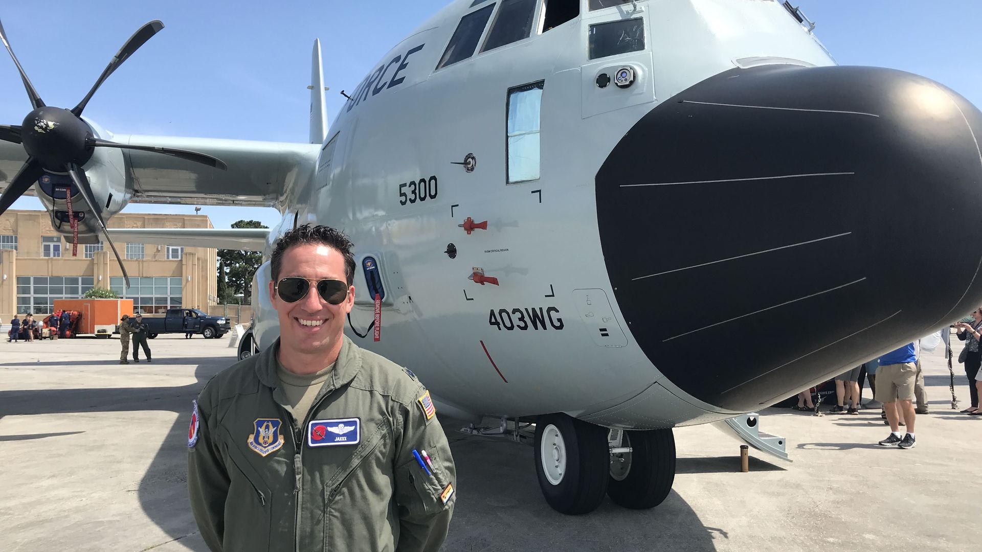 Photo shows John "Jaxxx" Gharbi standing in front of the Air Force Reserve's Hurricane Hunter aircraft. He's wearing his uniform jumpsuit and aviator-style sunglasses. It is a sunny day with blue skies at the Lakefront Airport in New Orleans.