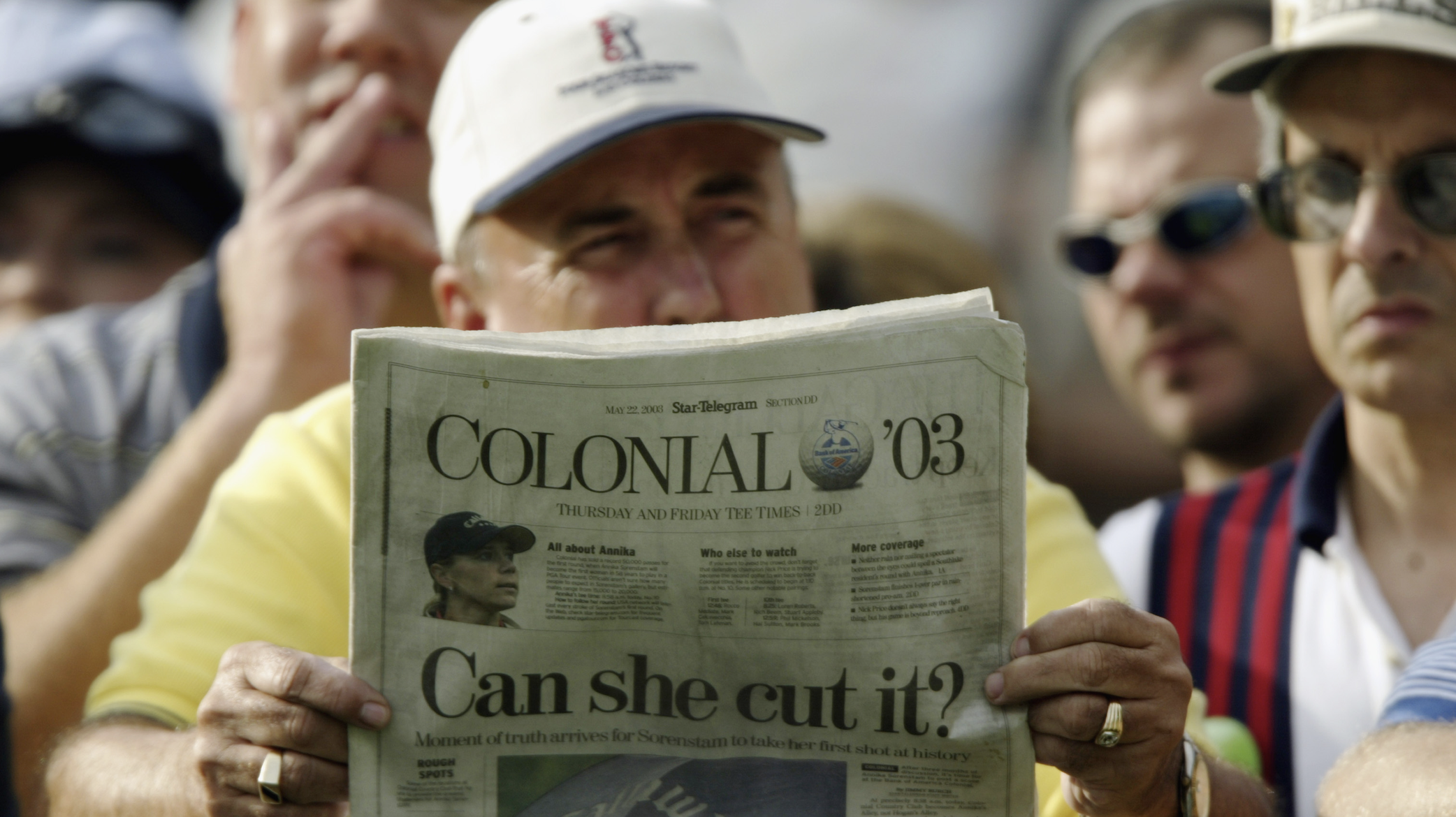 A man reads a newspaper with the front page that says "Can she cut it?"