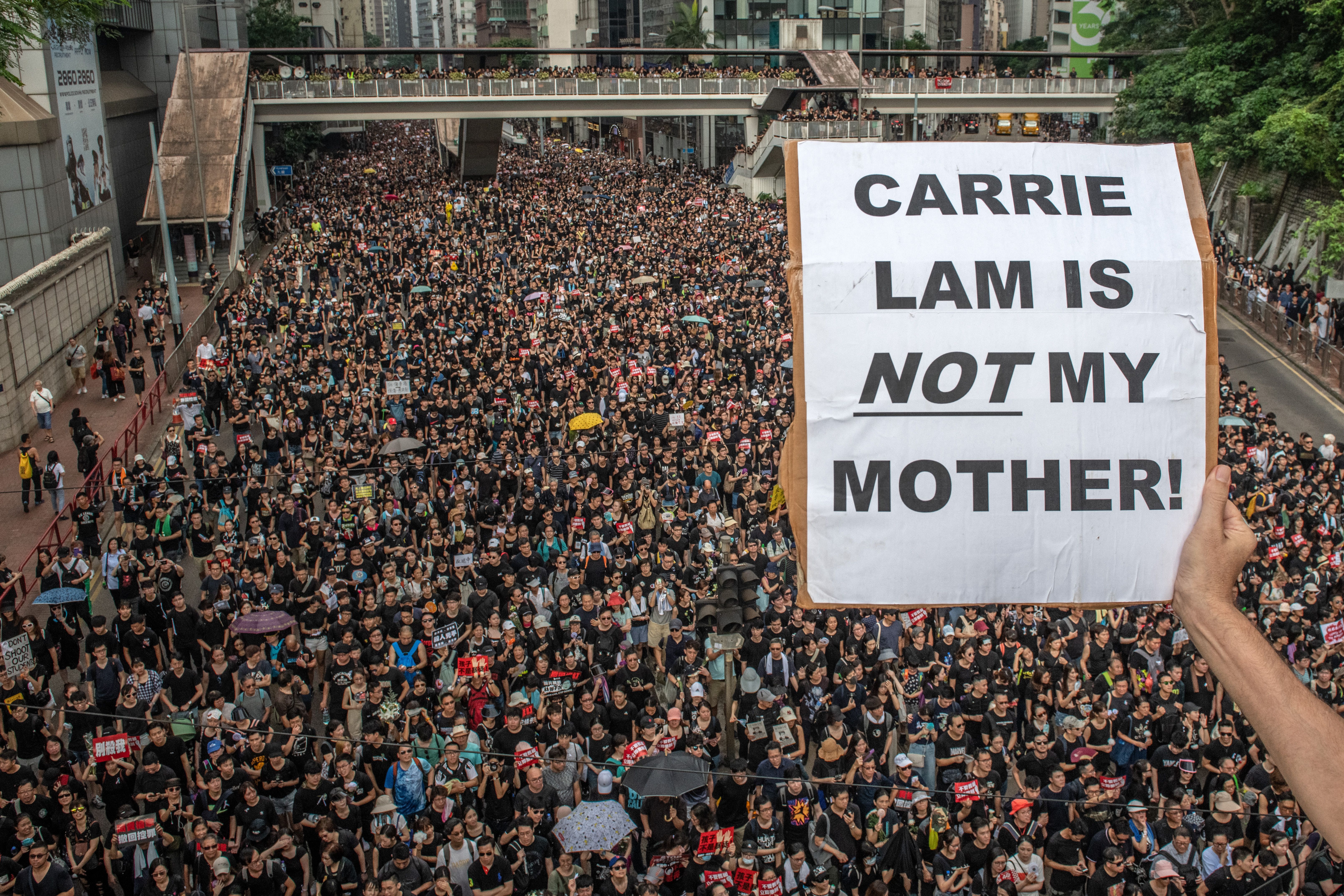: A protester holds a placard from a bridge as others march beneath during a demonstration against the now-suspended extradition bill on June 16, 2019 in Hong Kong.