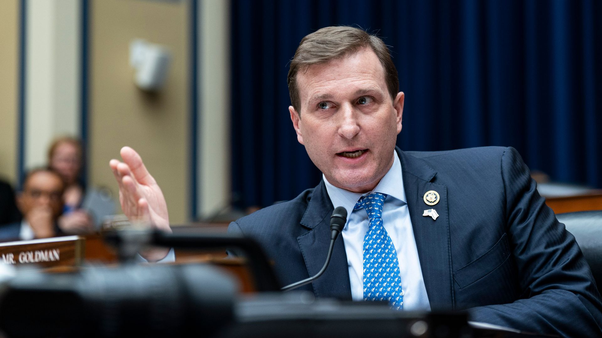 Rep. Dan Goldman, wearing a blue suit, white shirt and blue tie, speaks at a committee hearing.