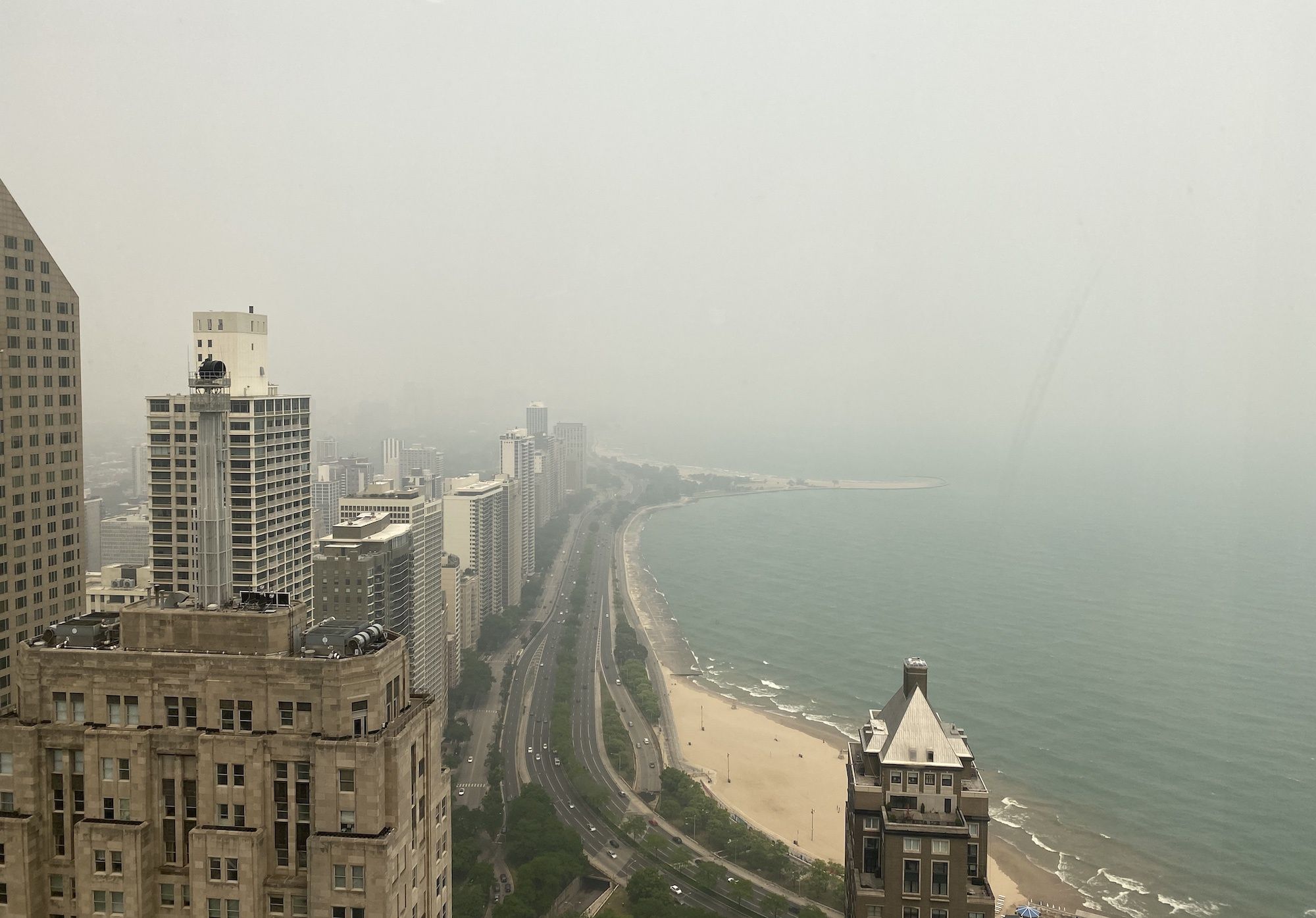 Photo of buildings and a lake shrouded in smoke/clouds. 