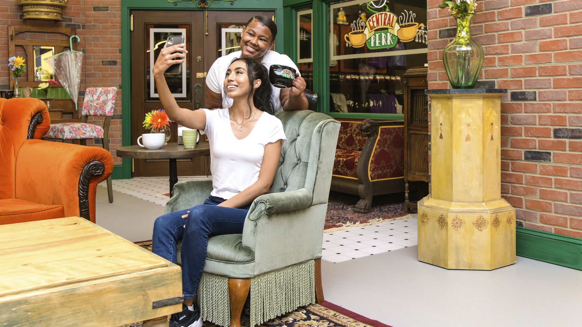 Two people pose for a photo in a recreated set of Central Perk from the TV show "Friends."