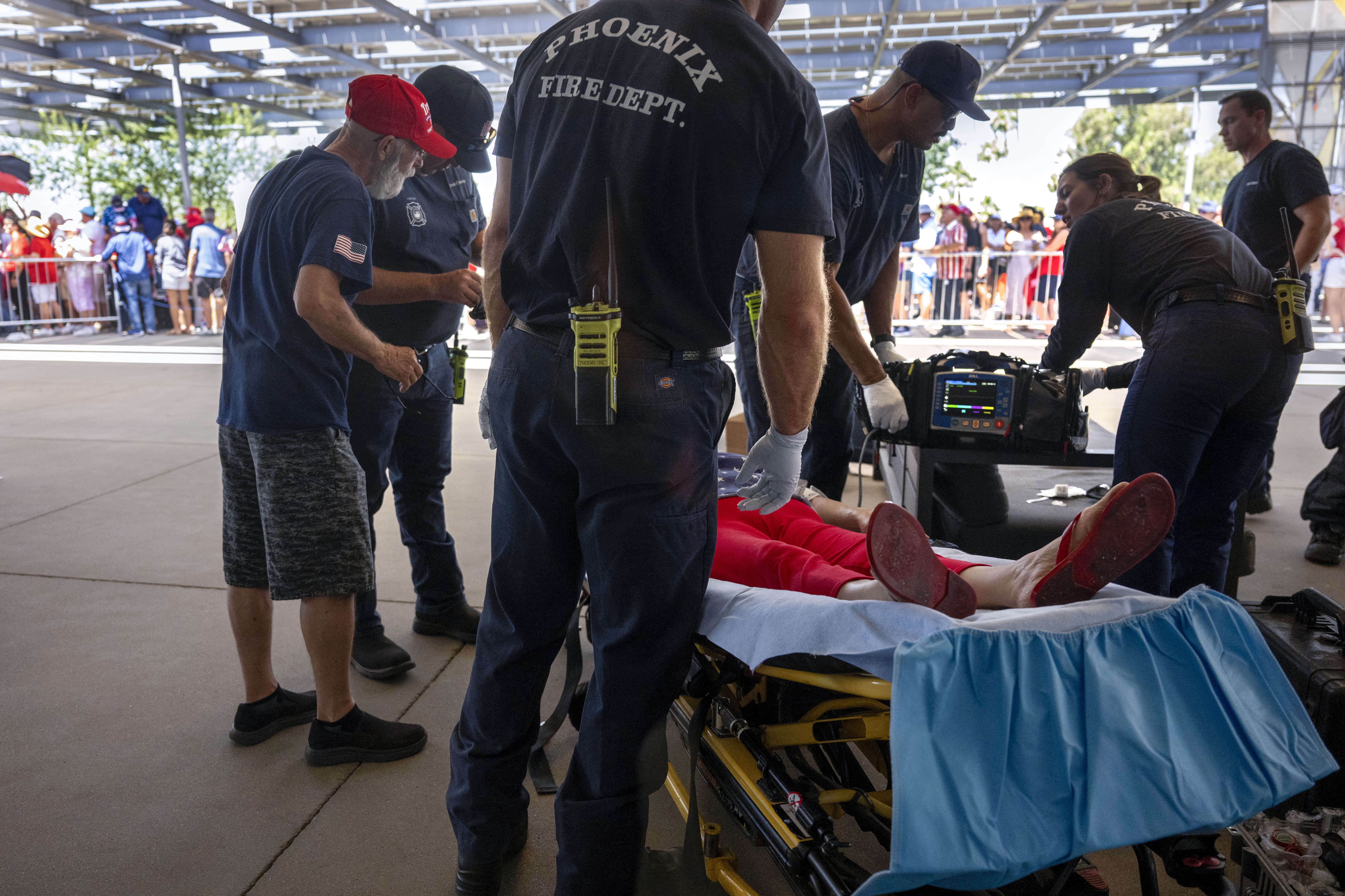 As temperatures reach 108 degrees Farenheit (42C), a woman is tended to for heat exhaustion as supporters line up before former US President and 2024 Republican presidential candidate Donald Trump participates in a town hall event at Dream City Church in Phoenix, Arizona, on June 6, 2024. 