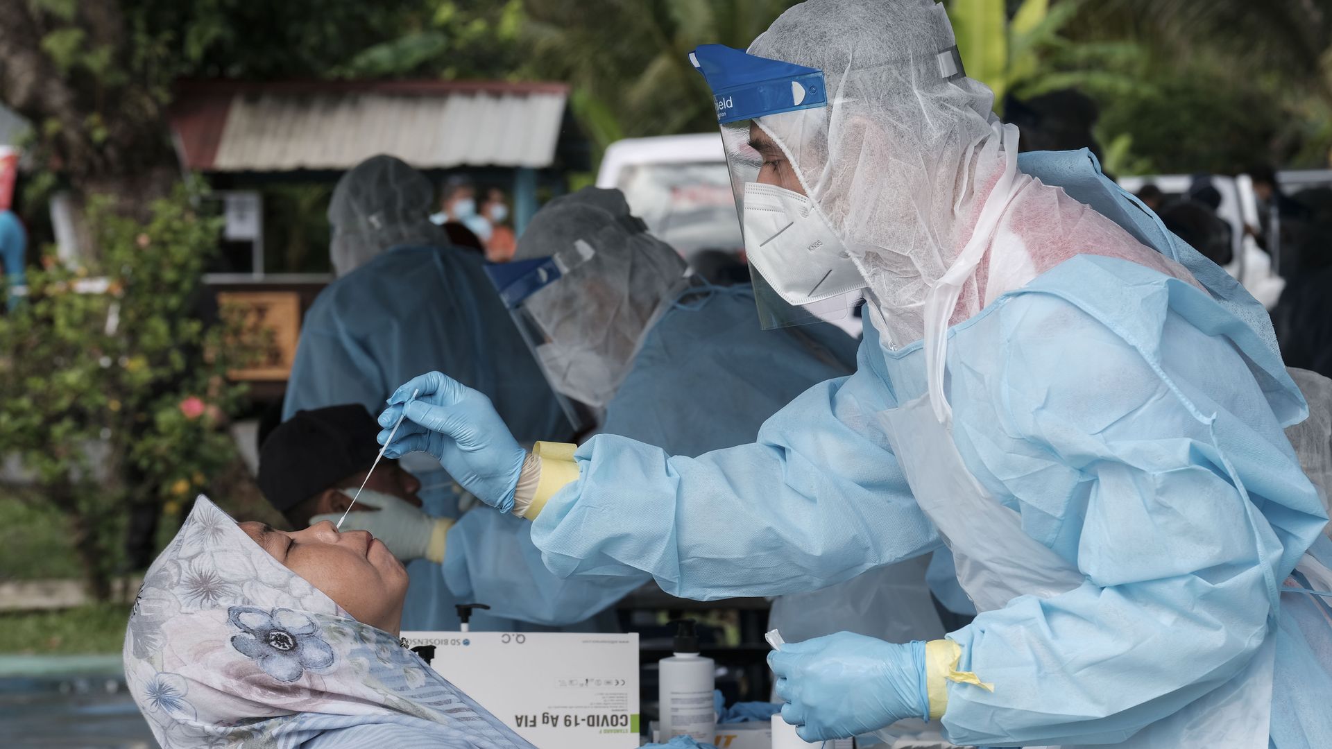 picture of a health professional wearing PPE taking a nasal swab sample from a patient