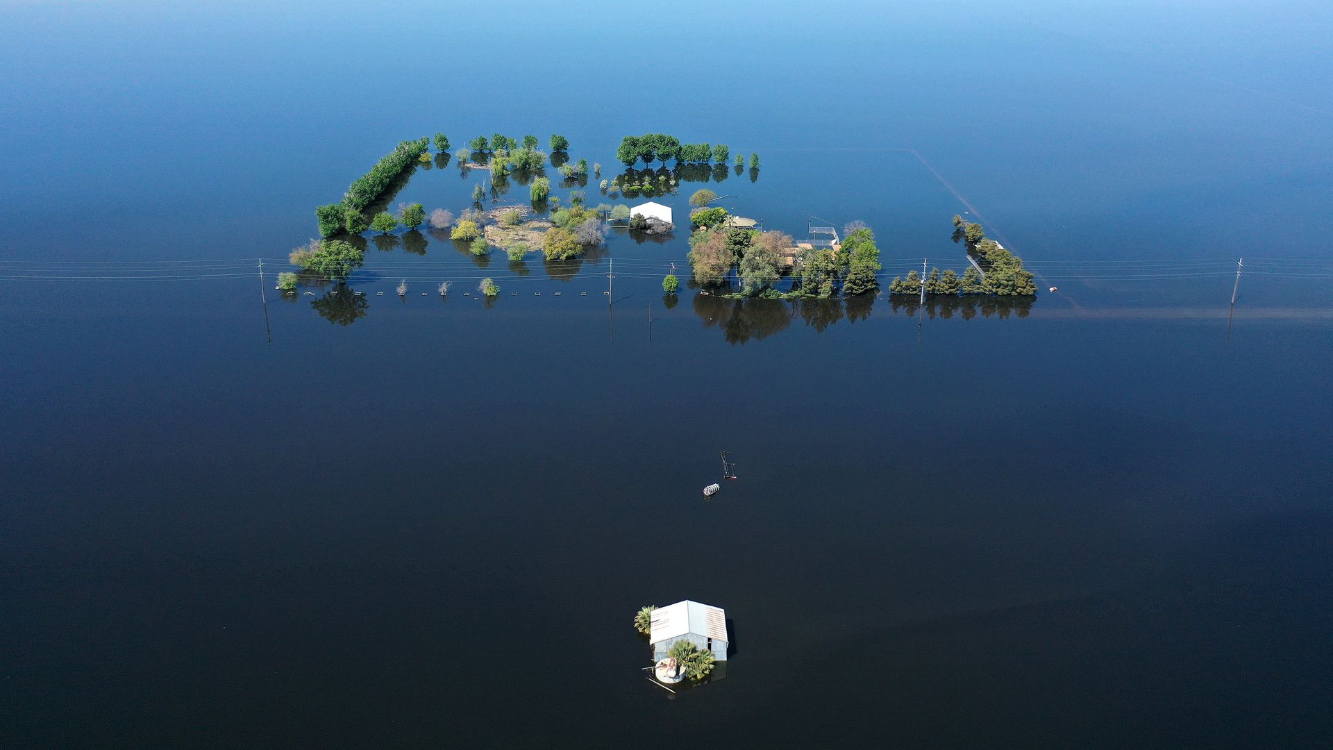  An aerial view of a home (C) surrounded by floodwaters in the reemerging Tulare Lake, in California’s Central Valley, on April 14, 2023 in Corcoran, California. 